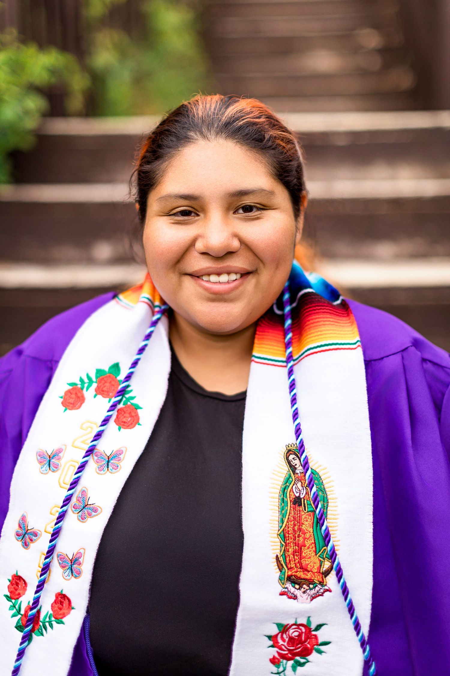 Cap and gown detail photo of Alejandra seated near dune grass at Van Buren Street Beach Access.