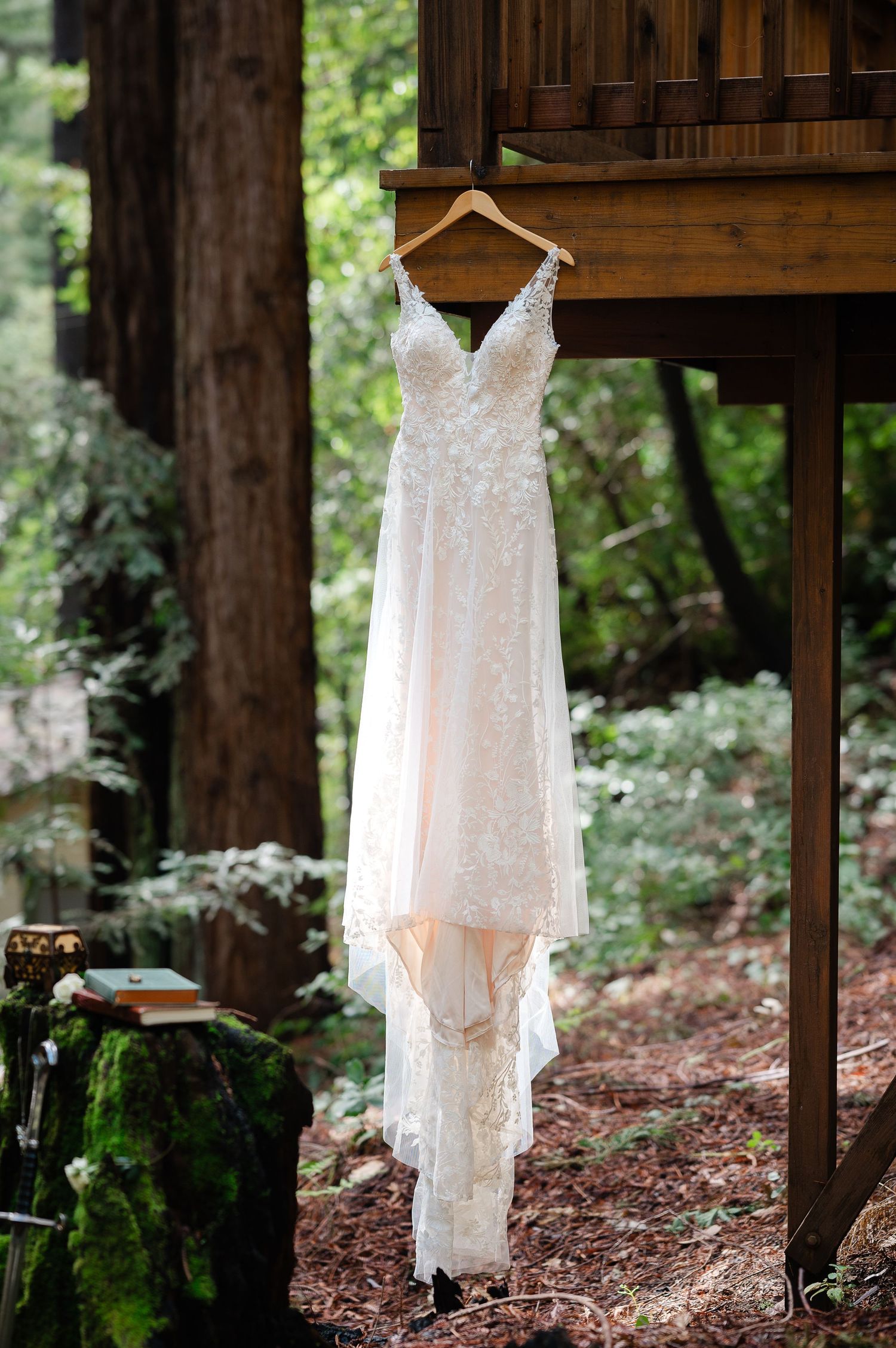 White leather ankle boots with small wooden heels displayed against lush green moss in a natural forest setting.