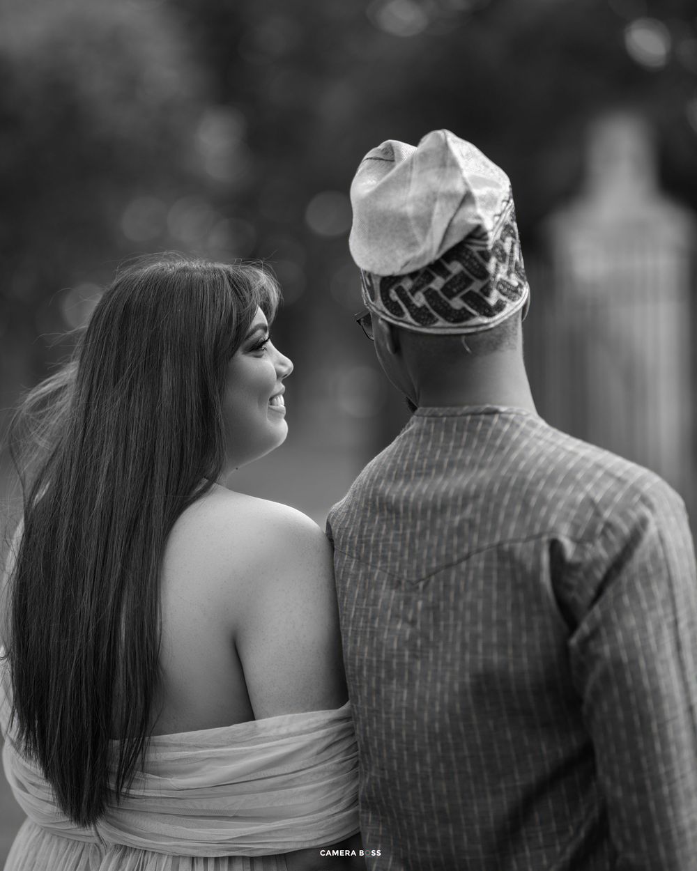 A couple shown from behind in monochrome, with one person in a strapless dress and another in casual attire.
