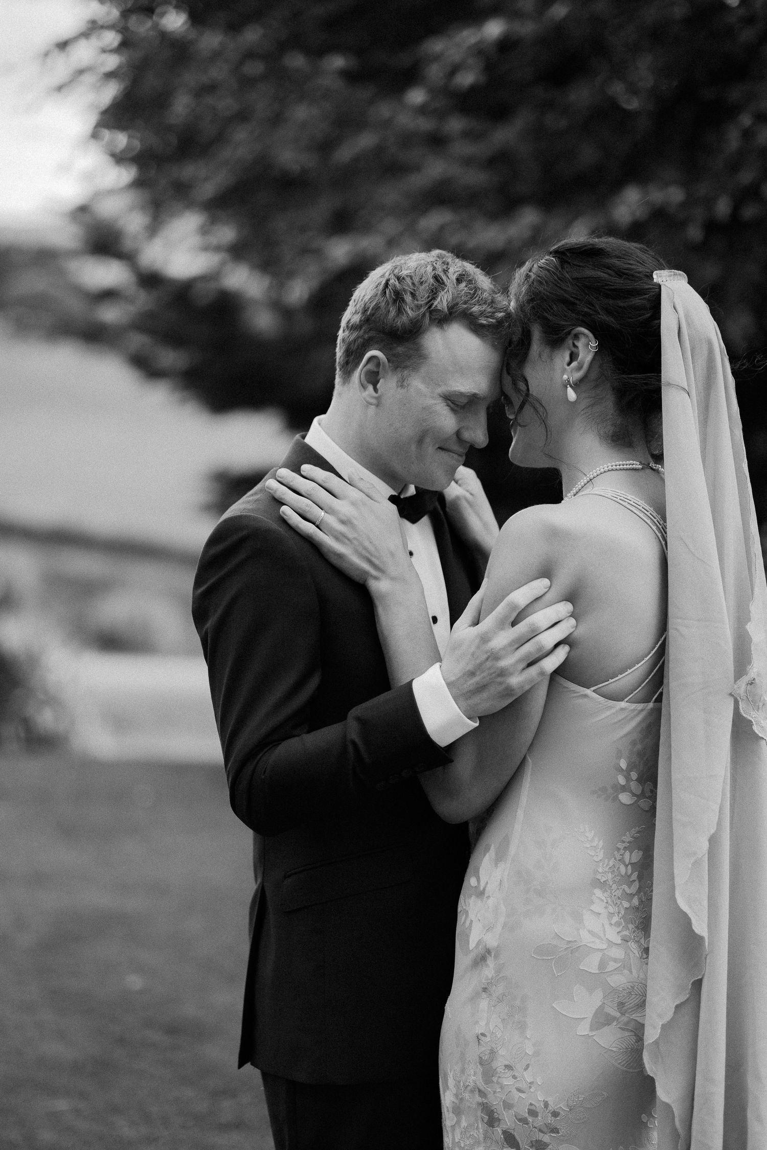 Two newlyweds share an intimate embrace in black and white wedding photos.