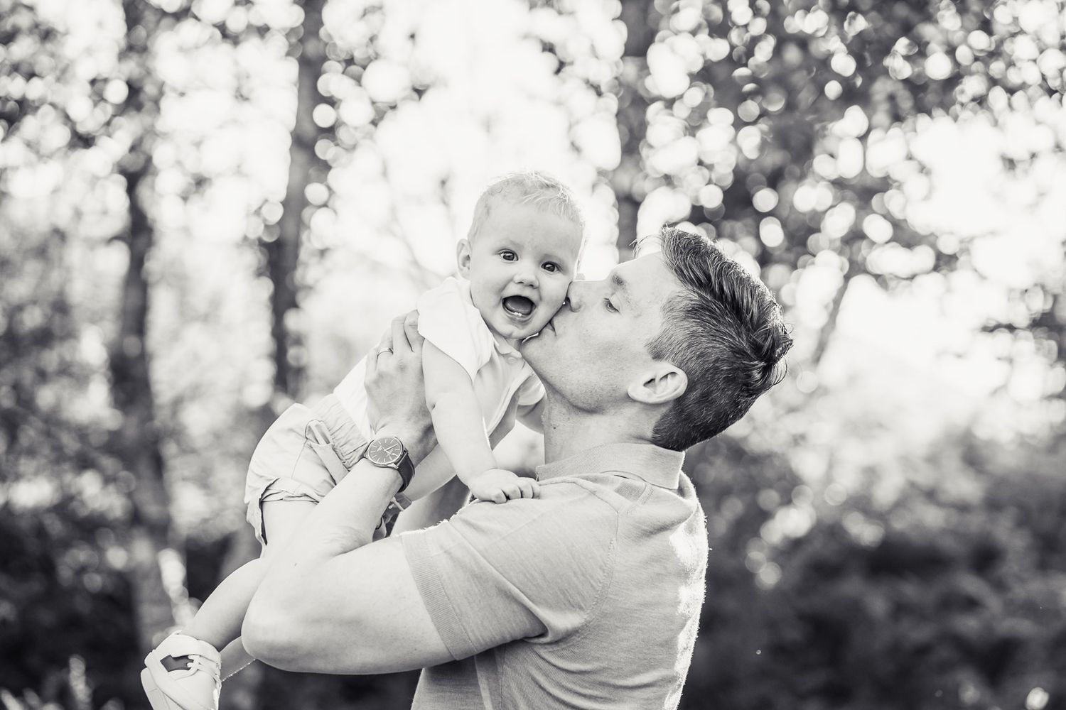 Dad kisses his son at sunset.