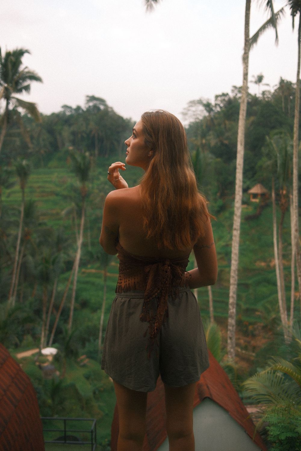 Scenic view of tropical palm trees and lush hillside terraces in Bali during golden hour.