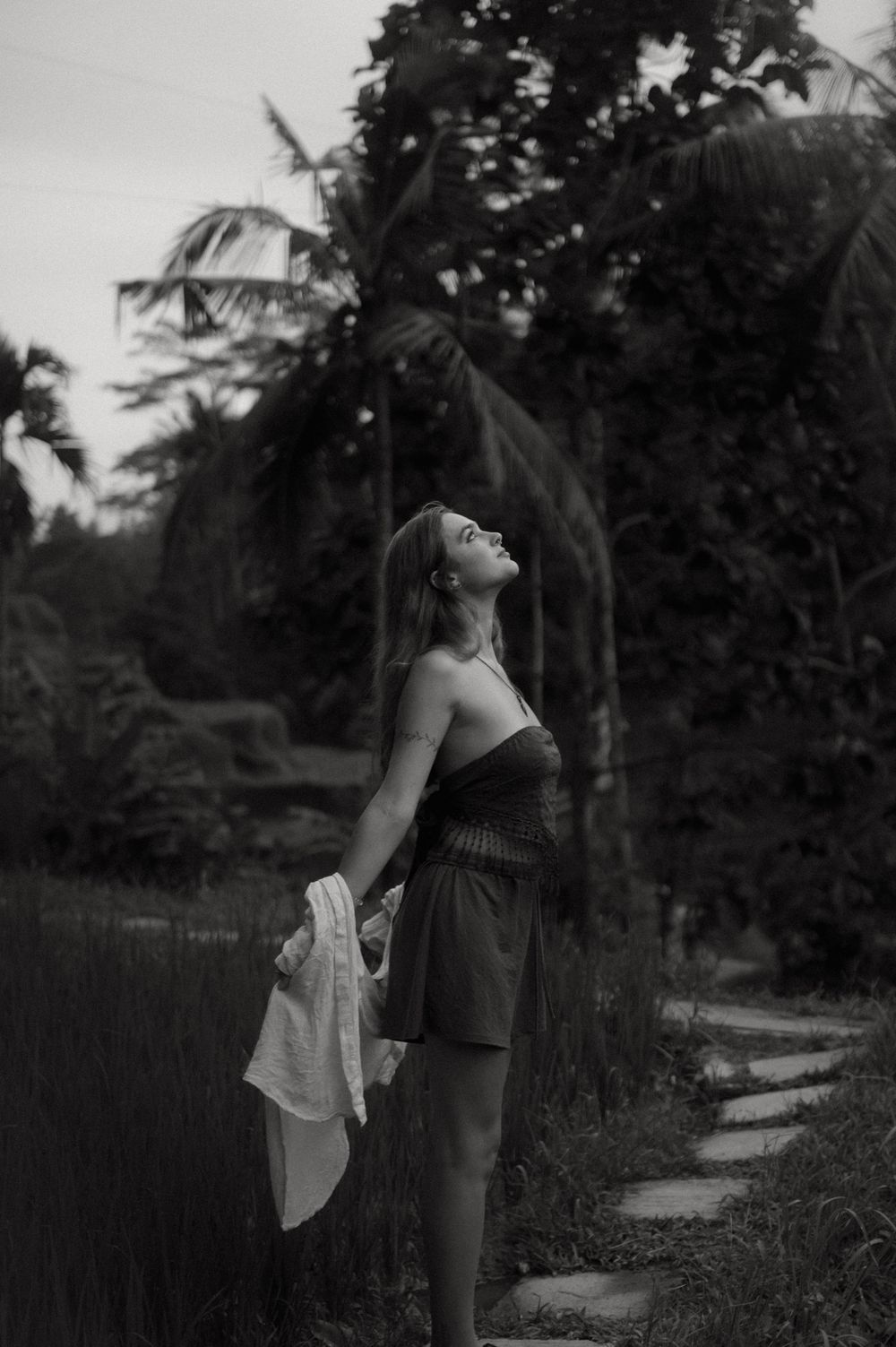 Dramatic black and white portrait in a tropical garden setting with palm trees.