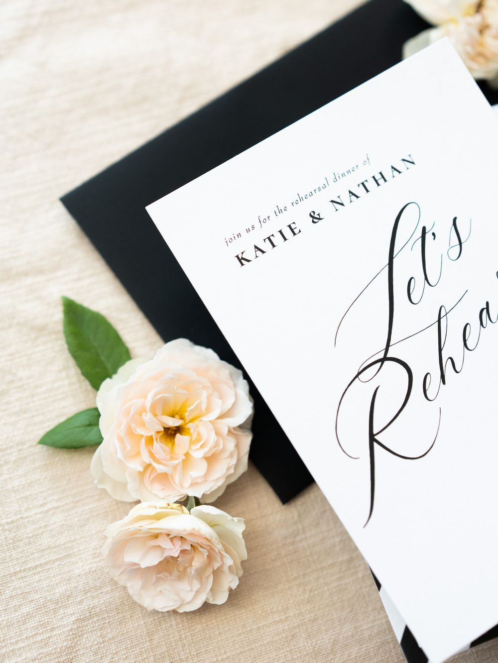 Elegant wedding invitation cards with peach roses and delicate calligraphy displayed on a white textured surface.