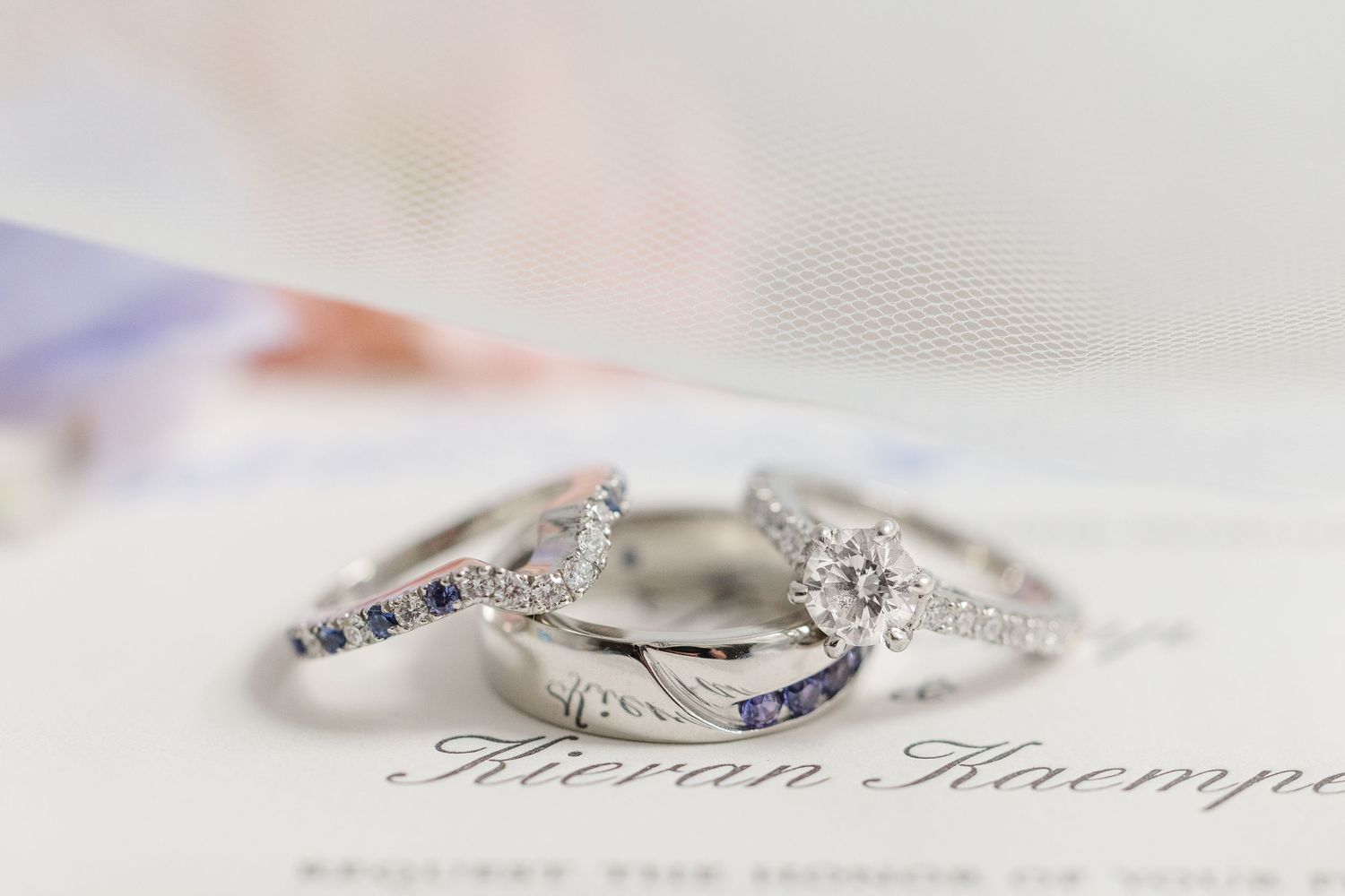 Two sparkling diamond wedding rings rest elegantly on what appears to be embossed text or an invitation.