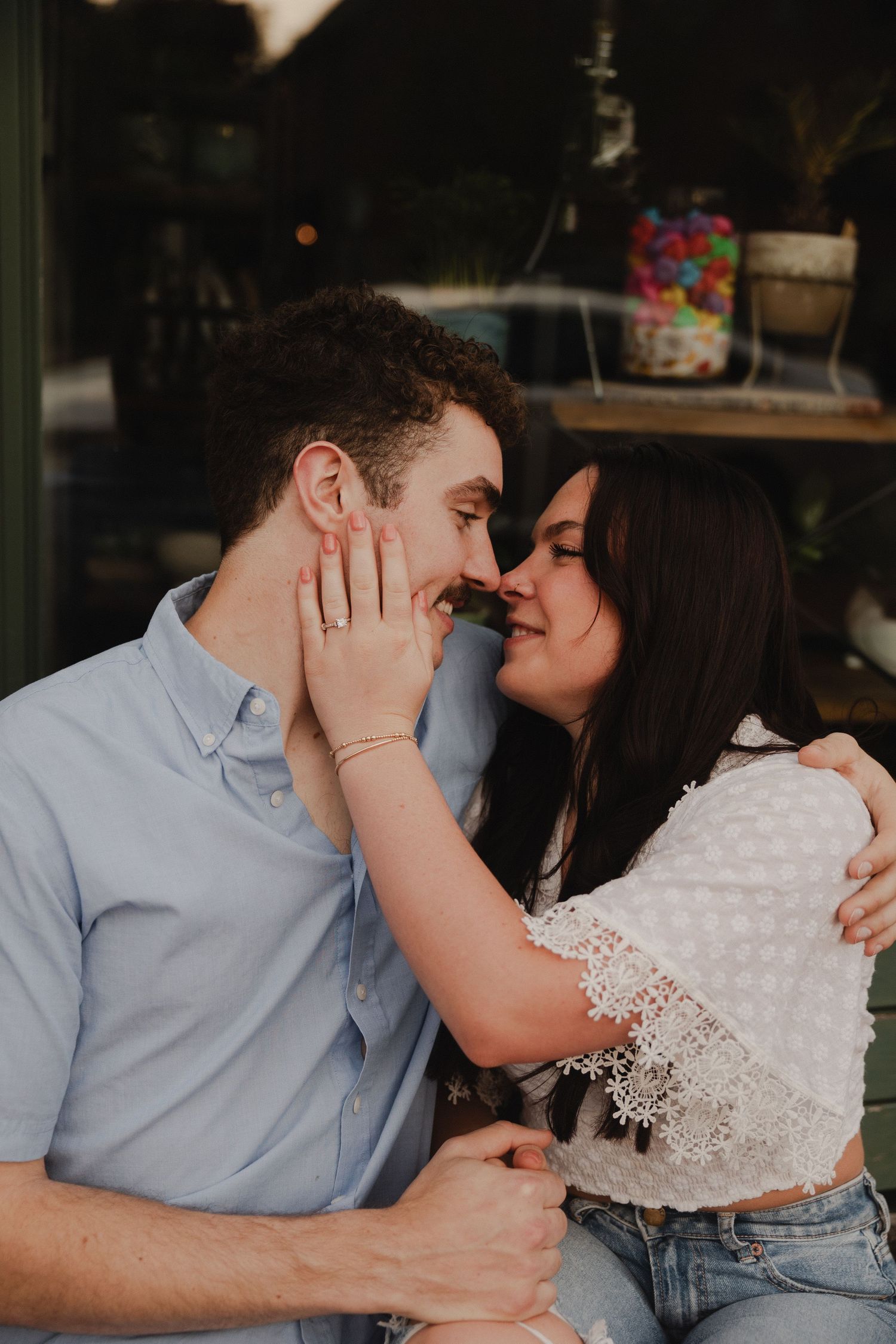 A couple shares an intimate moment in front of a window display.