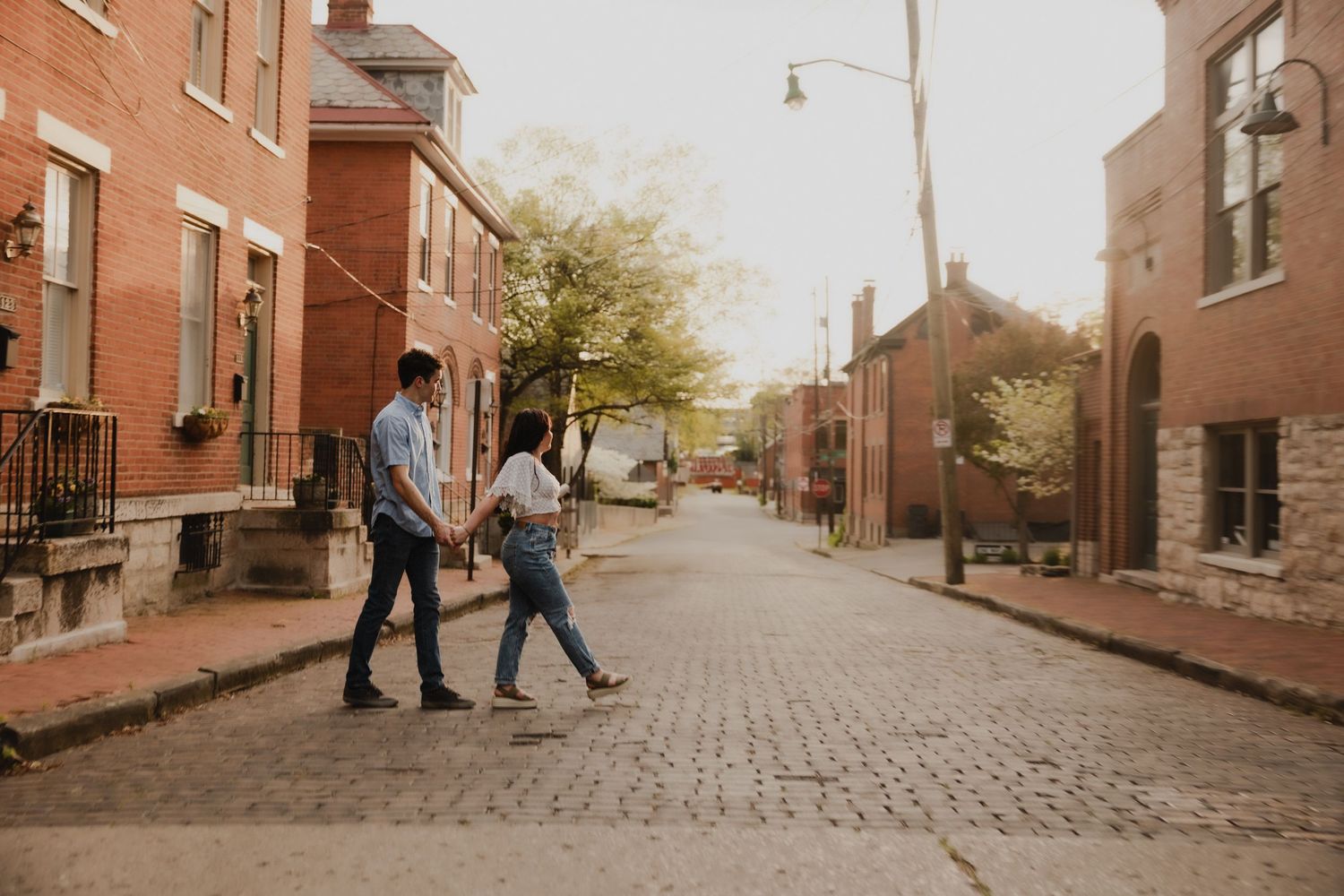 Couple walking together on historic cobblestone street lined with brick buildings.