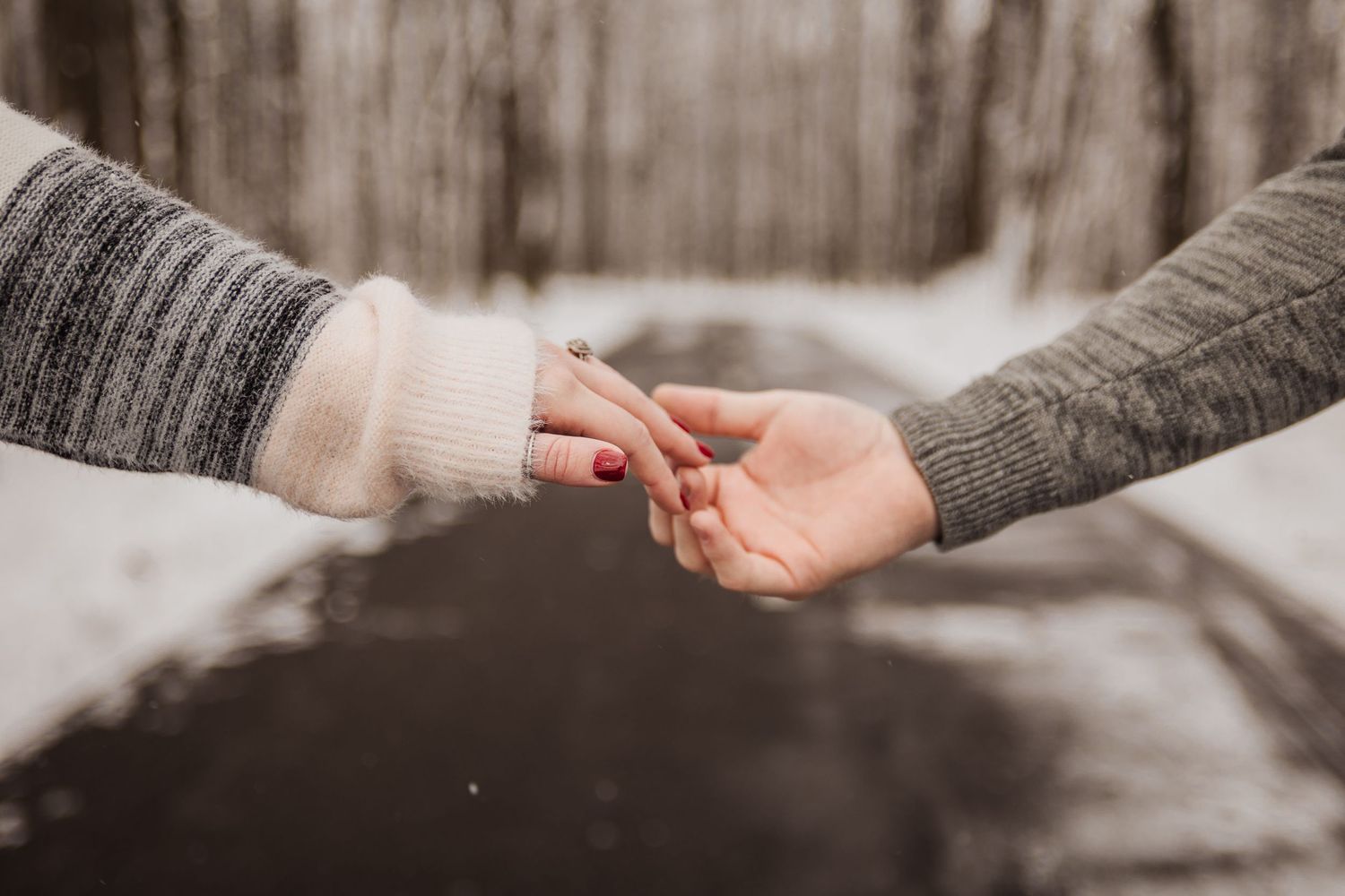 Close-up shot of two hands reaching for each other in the snow.