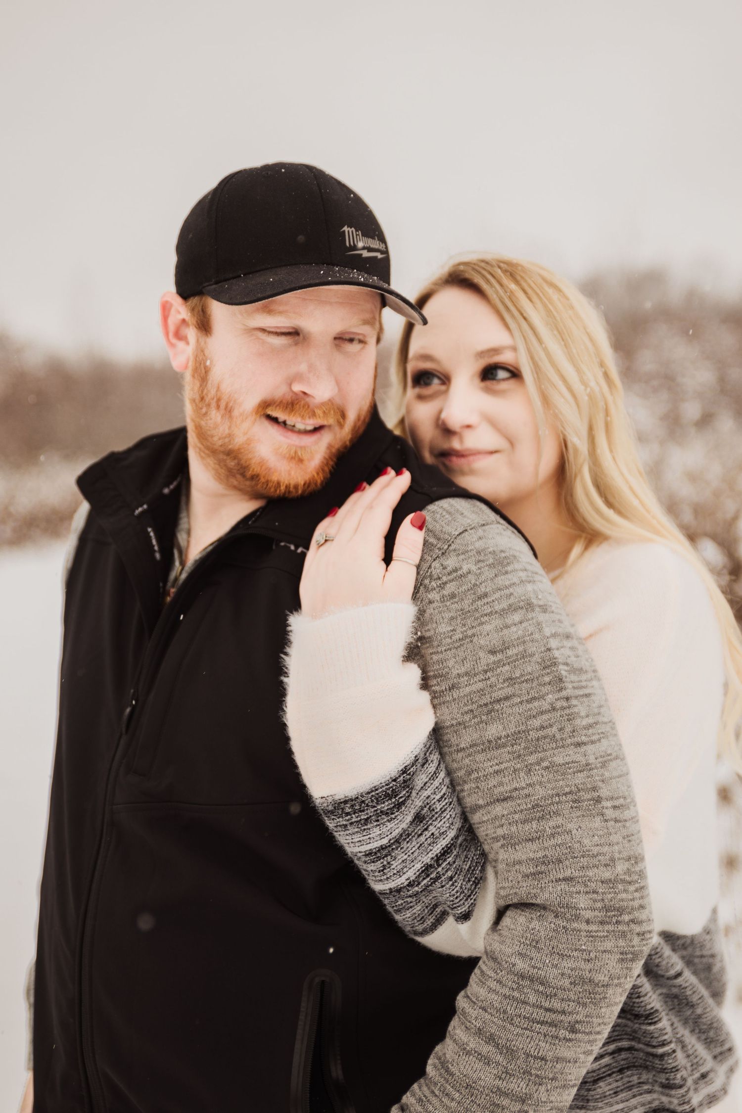 Couple sharing a tender moment while wearing casual winter clothing in the snow.