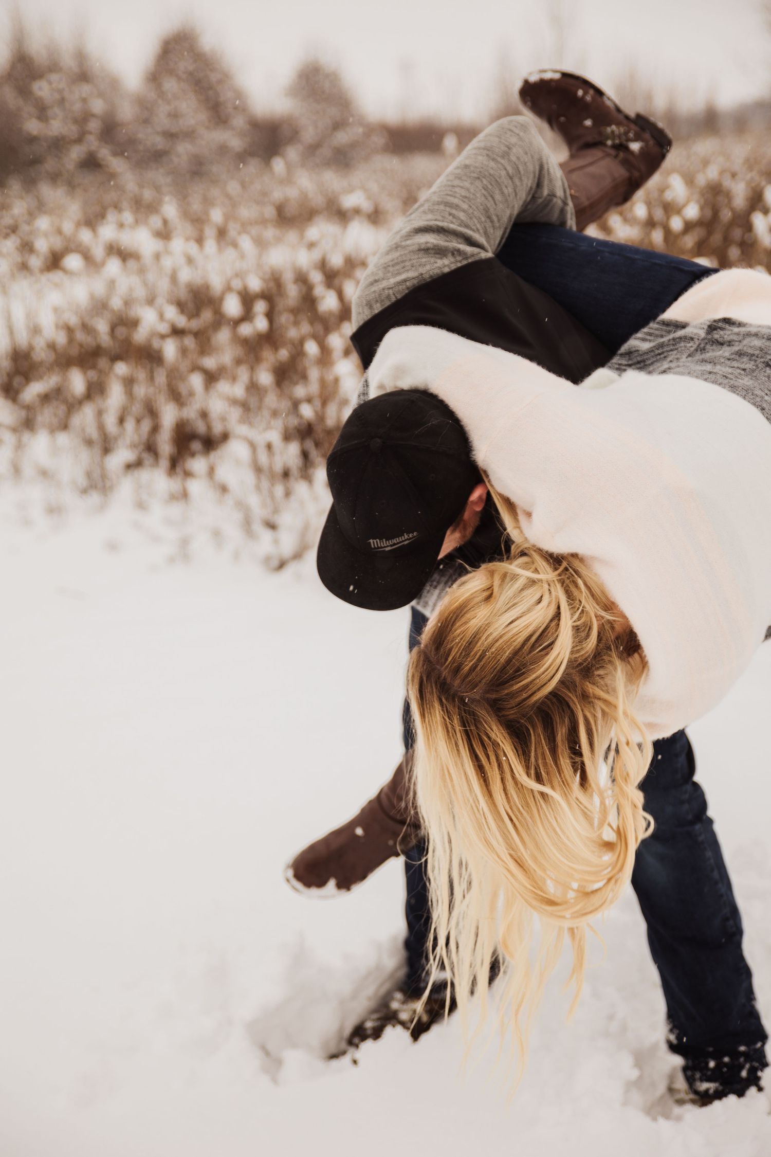 A playful winter engagement photo with a couple being silly in the snow.
