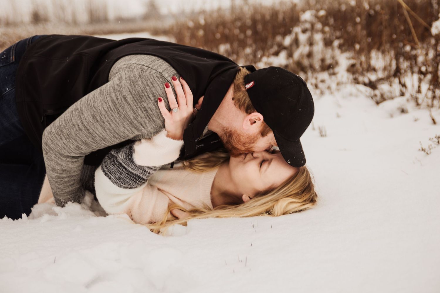 A romantic photo of a couple sharing a playful moment in the snow.