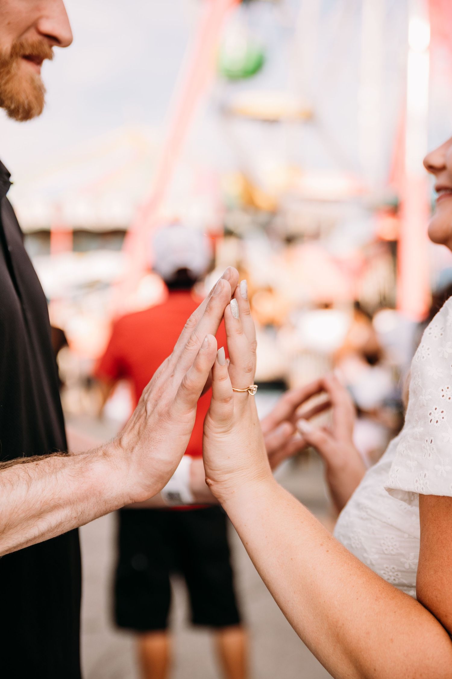Two people press their palms together in a playful moment at a carnival.