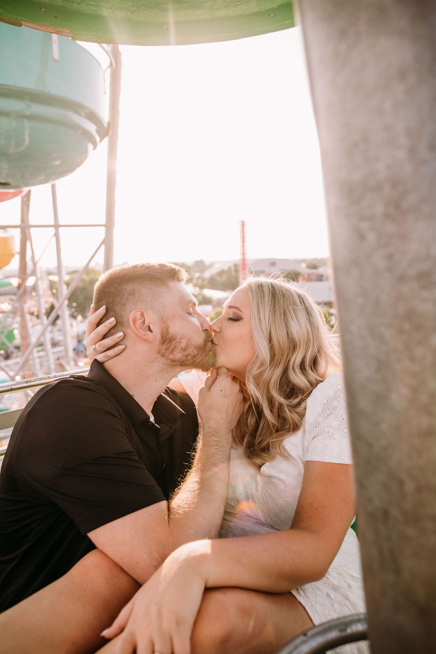 A couple shares a romantic kiss while riding on a carnival attraction.