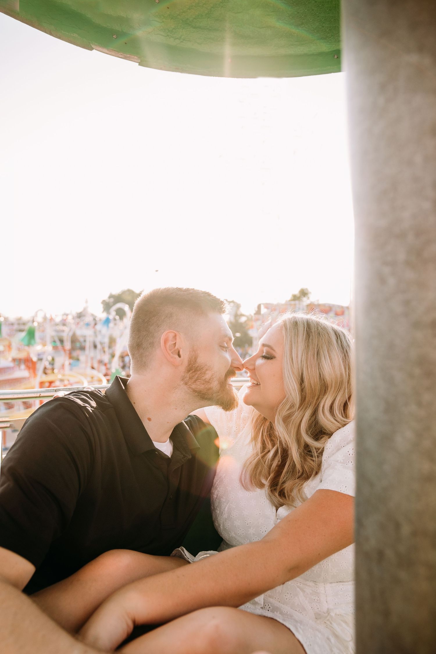 A couple laughs together while enjoying a sunny day at a carnival.
