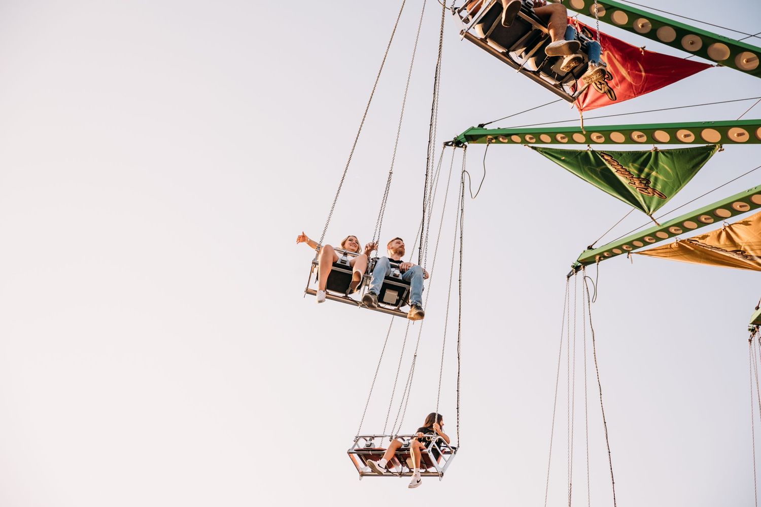 Aerial view of carnival swing ride with multiple seats suspended in air.