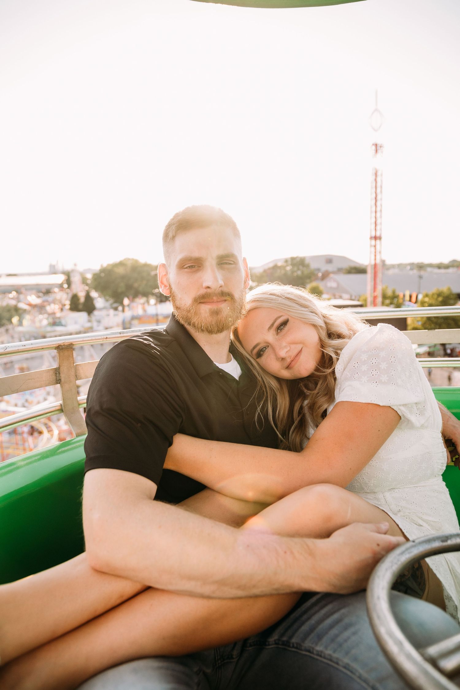 Couple cuddling together on a Ferris wheel ride during golden hour.