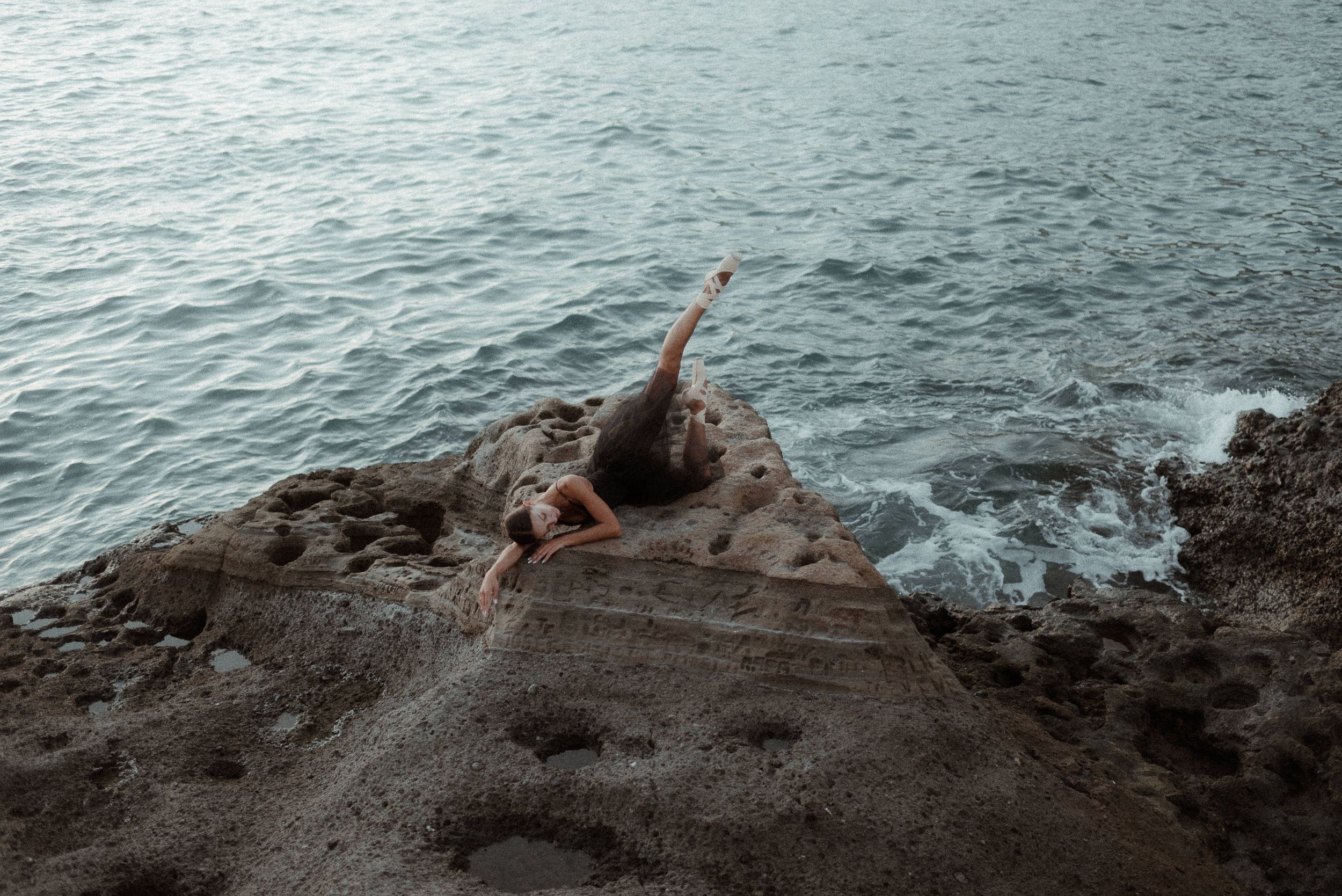 A dancer performs on rocky cliffs overlooking dramatic ocean waves.Tenerife Wedding Photographer in La Caleta de Adeje.