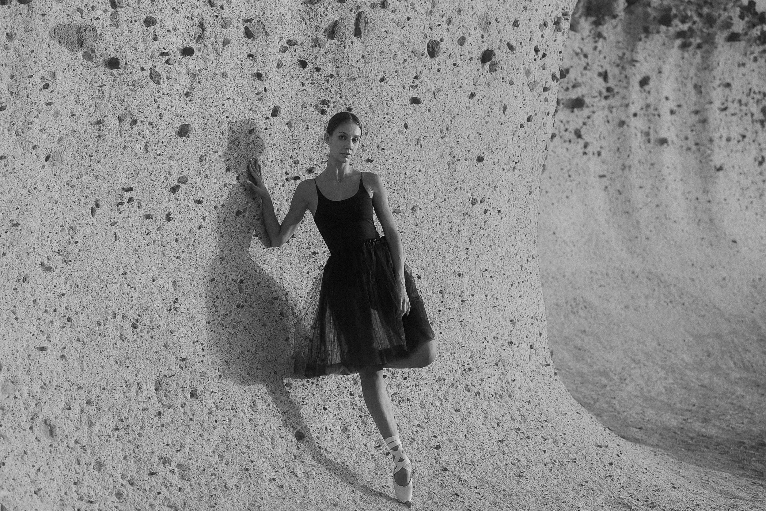 A black and white image of a ballet dancer posing against a textured wall. Tenerife Wedding Photographer in La Caleta de Adeje.