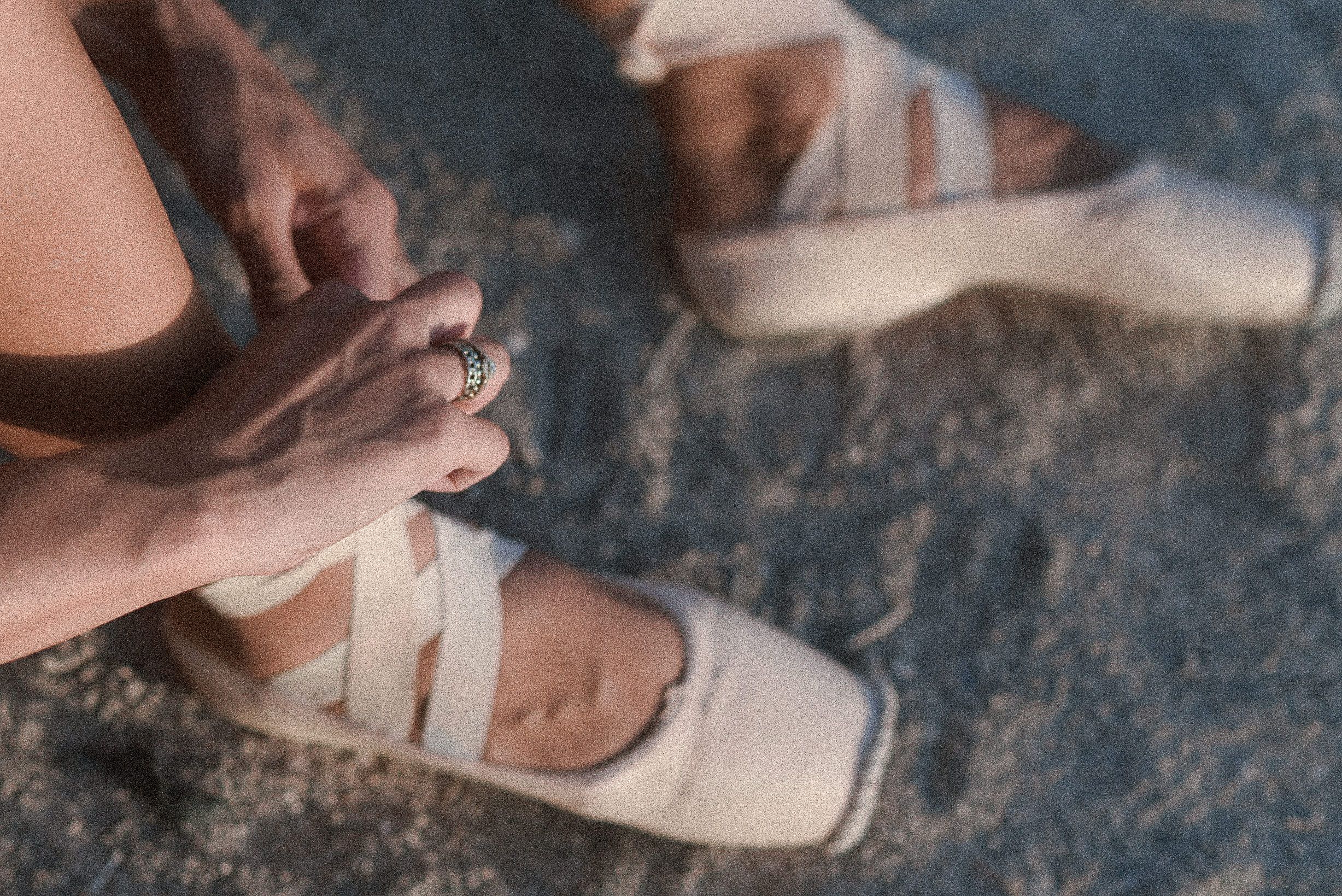 Close-up of ballet pointe shoes being tied with satin ribbons on stone surface. Tenerife Wedding Photographer in La Caleta de Adeje.