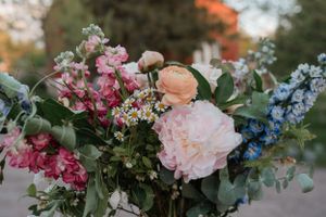A romantic floral arrangement with pink, blue, and peach blooms mixed with greenery.
