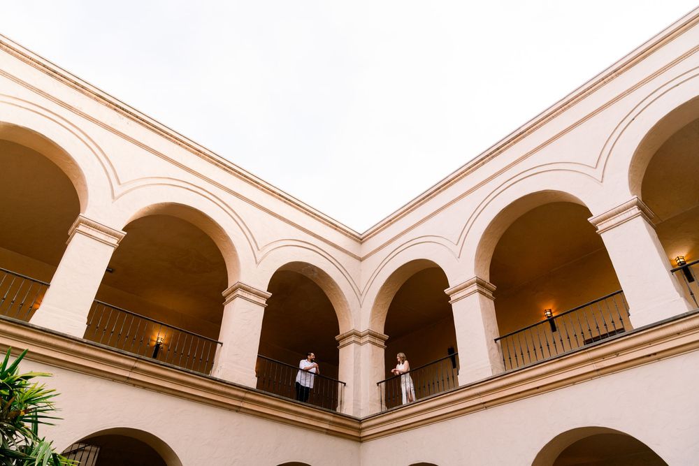 Colonial style building's elegant interior courtyard features a balcony with white arches and warm lighting.