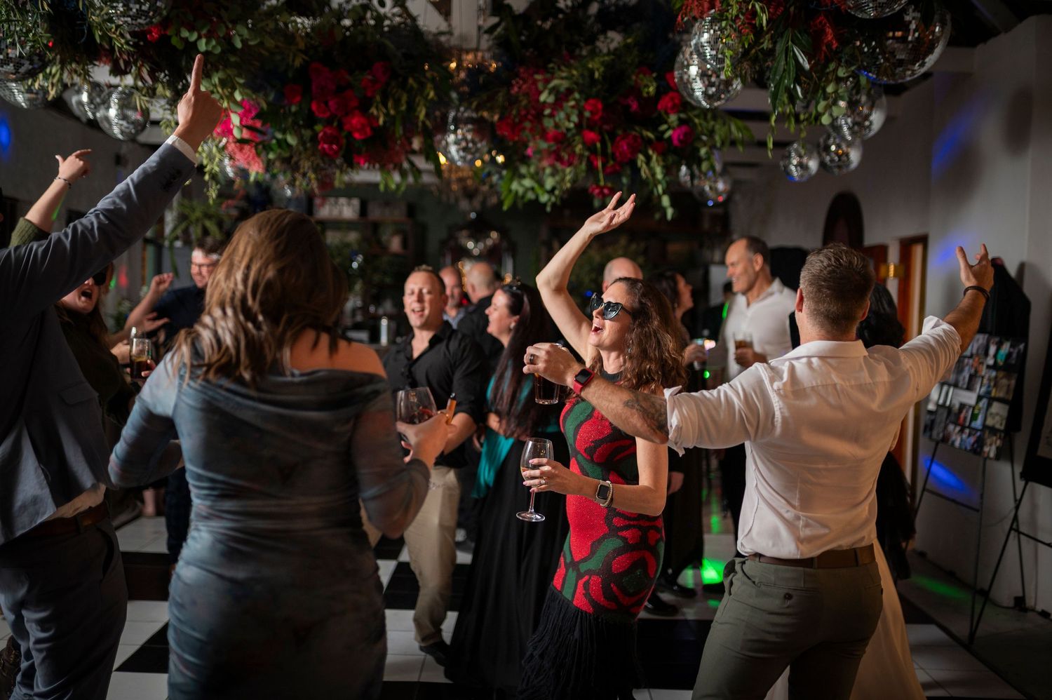 People dancing together at a lively indoor party with colorful lighting in a dimly lit space.
