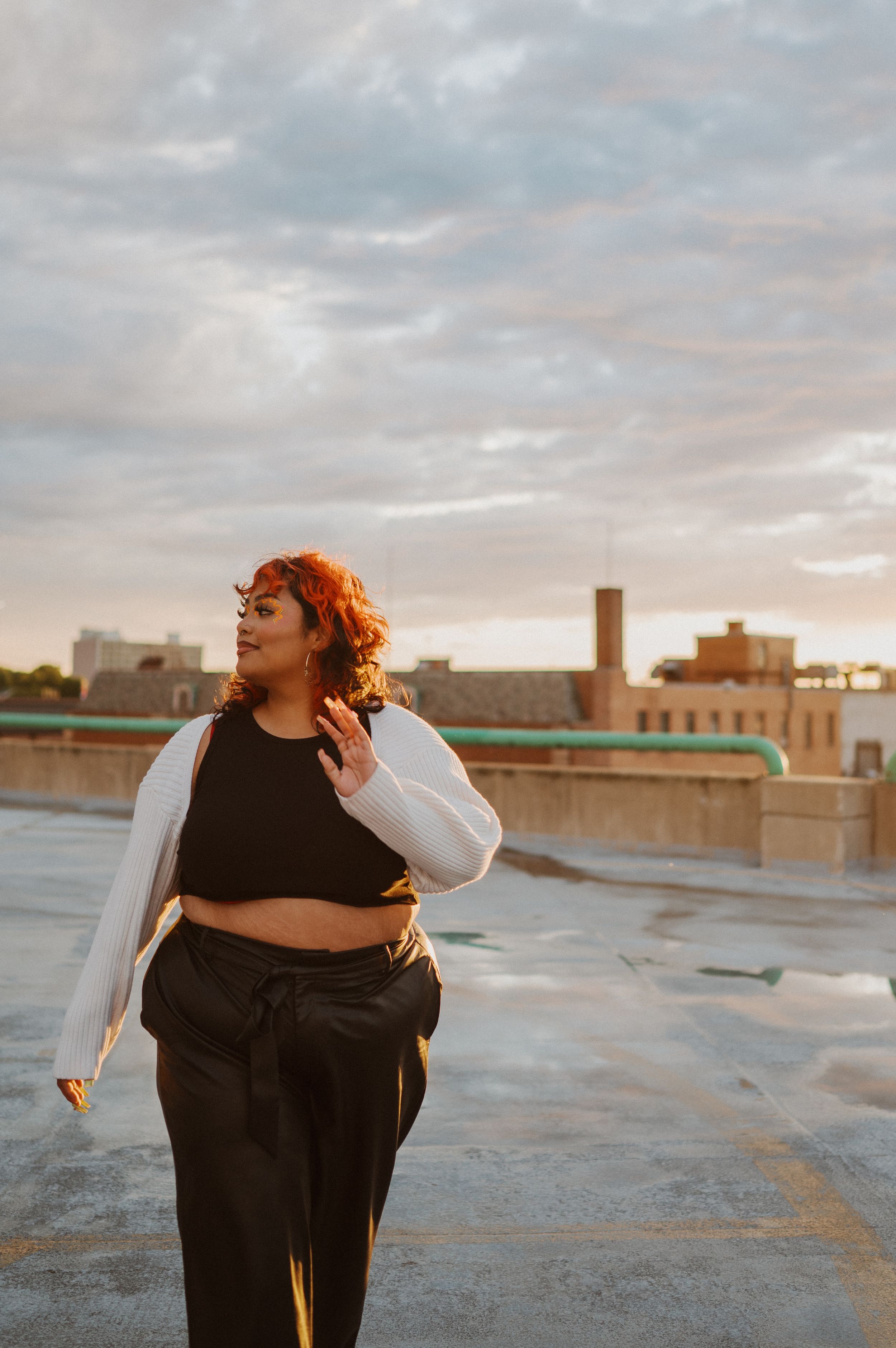 A fashion photoshoot on an urban rooftop during golden hour shows confidence and style.