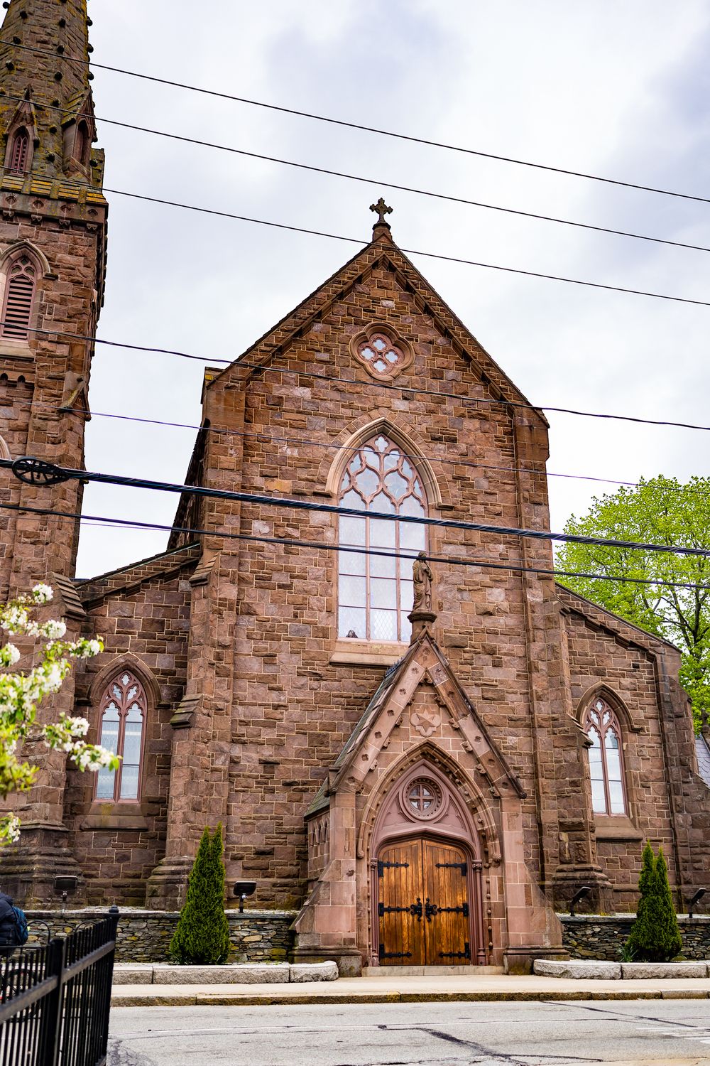 Historic stone church with Gothic architecture and arched windows against cloudy sky.