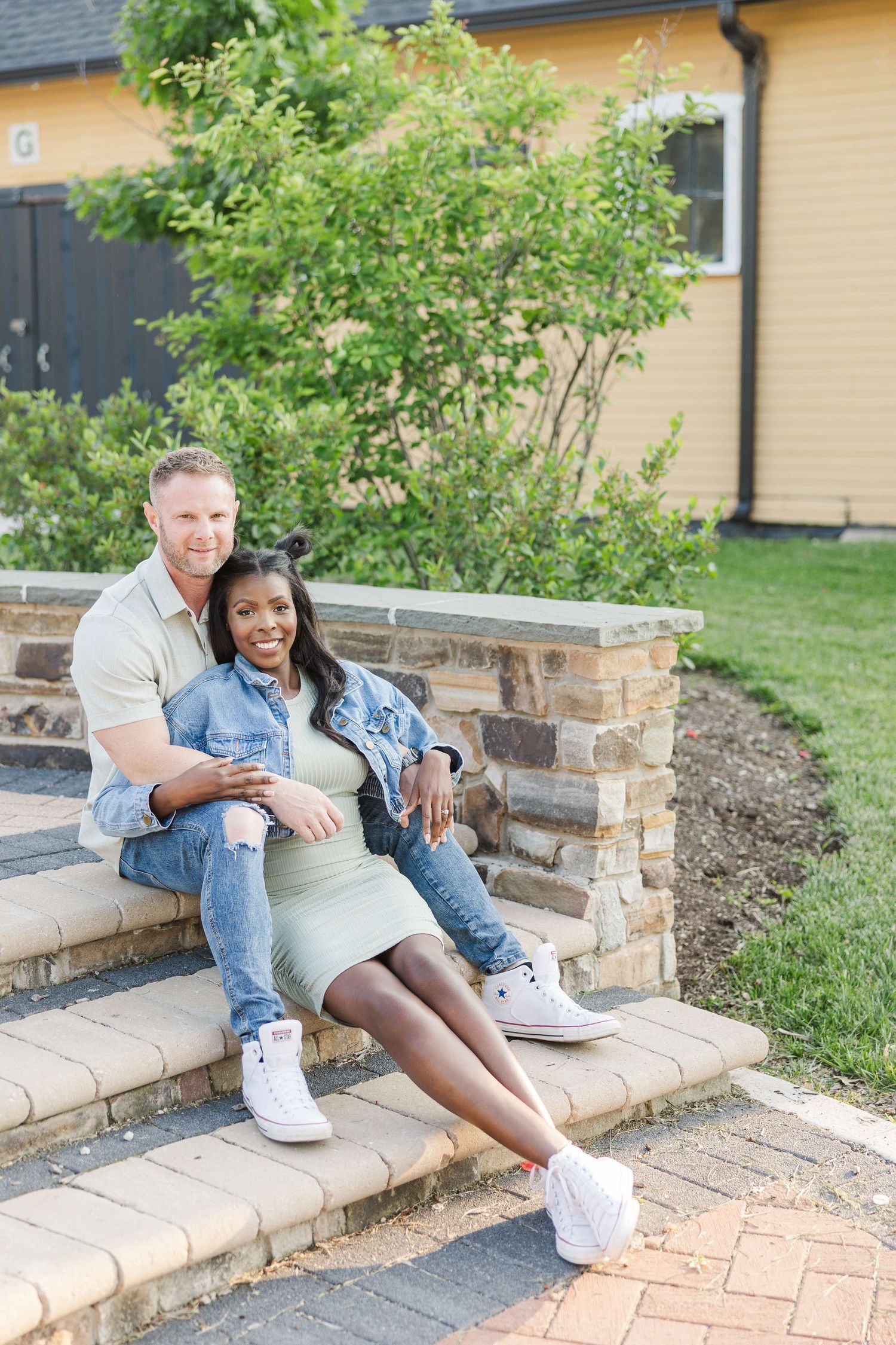A couple sits casually together on outdoor stone steps during a photo session.