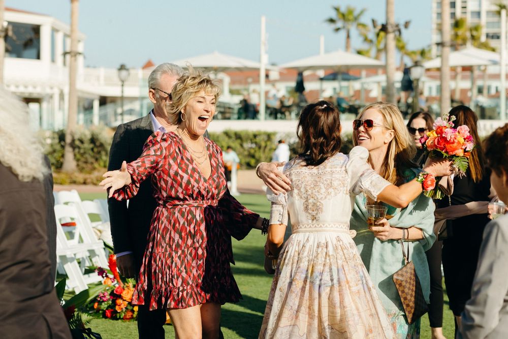 Joyful wedding celebration with guests dancing outdoors on a sunny day.