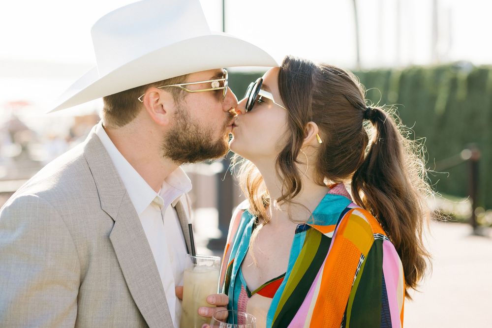 A romantic sunset kiss between wedding attendees on a bright sunny day.
