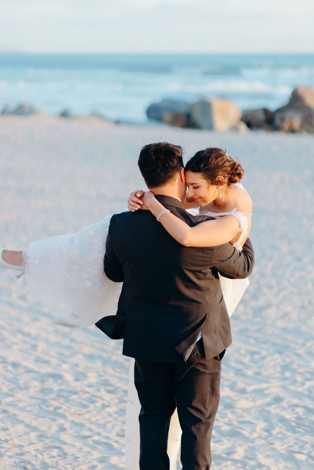 A romantic sunset embrace on a sandy beach with ocean waves in the background.