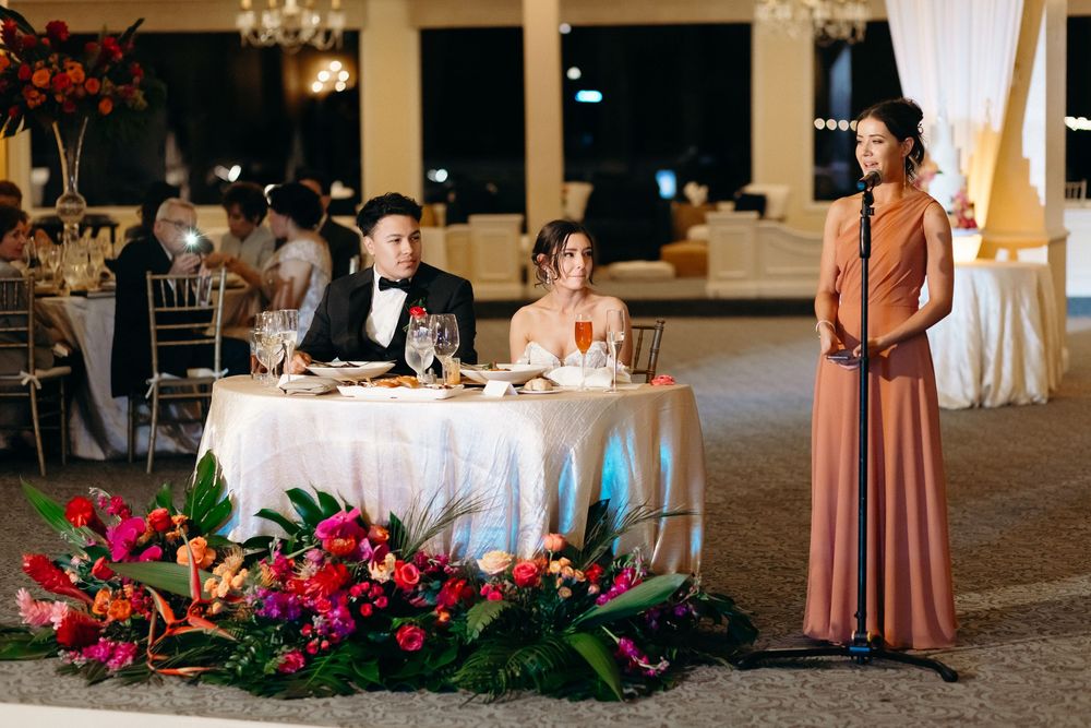 Reception table decorated with vibrant red floral arrangements in an elegant ballroom.