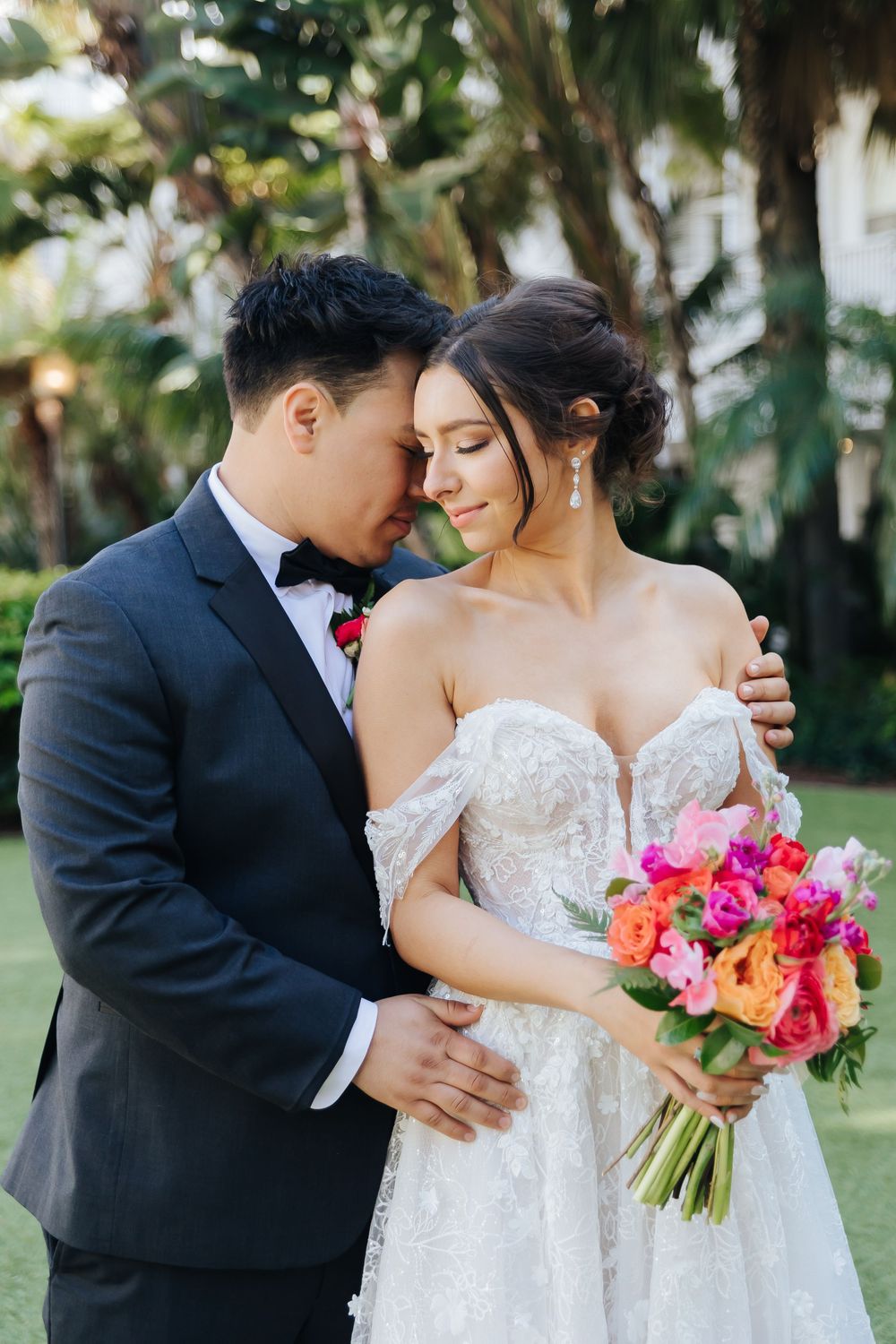 A romantic moment captured between newlyweds with tropical flowers and palm trees in the background.