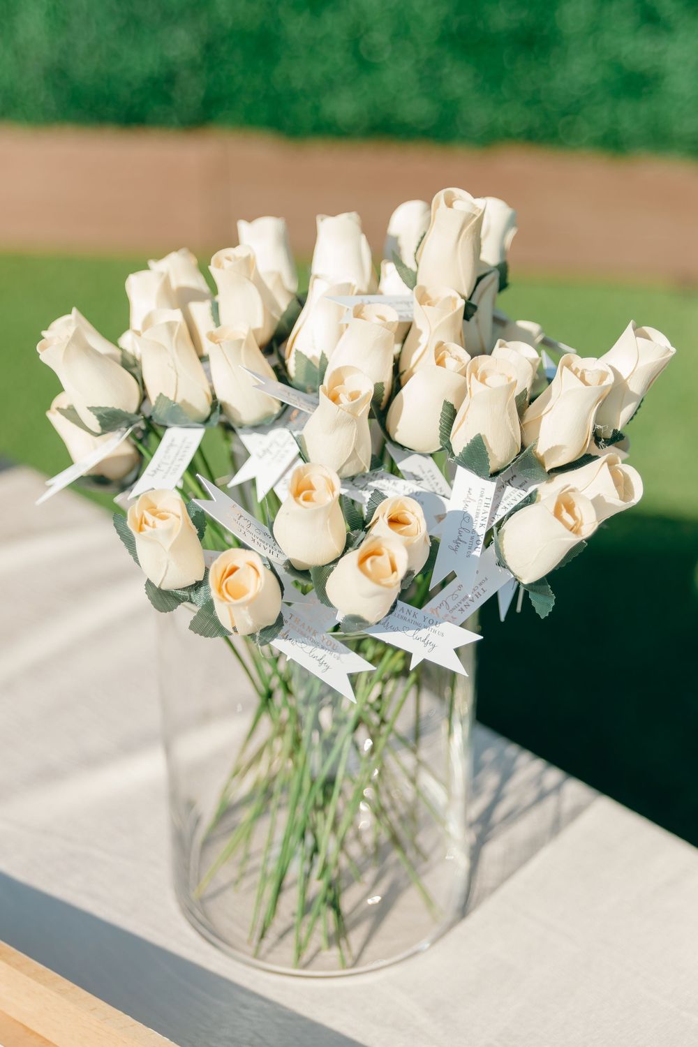 Elegant white roses arranged in a clear glass vase with delicate ribbons tied around each stem.
