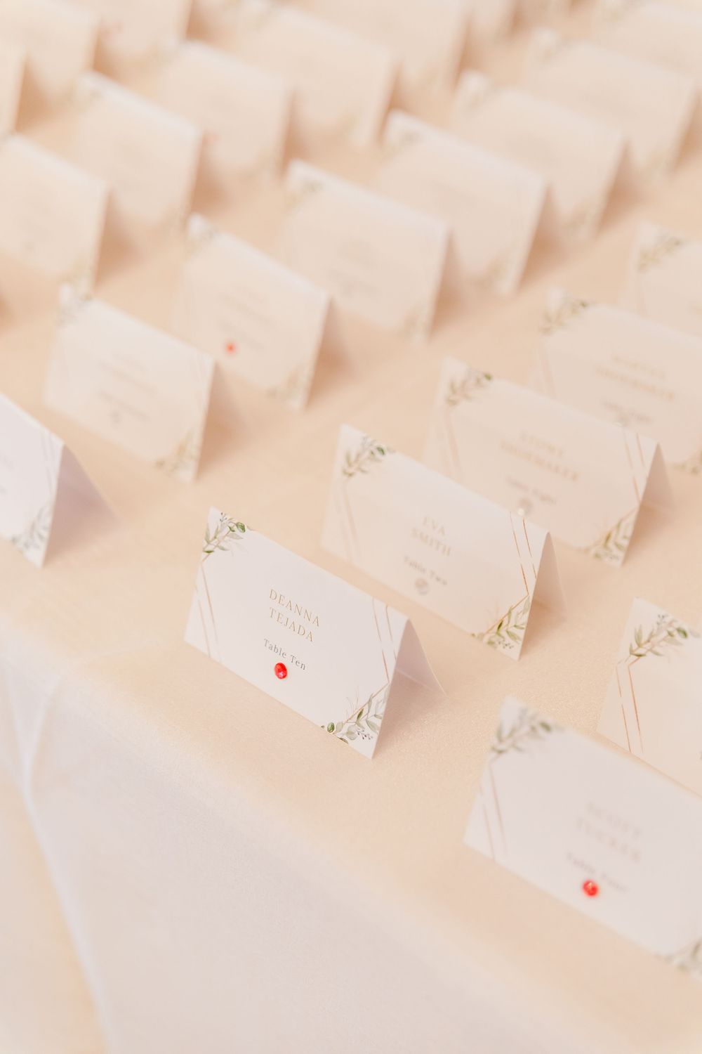 Rows of elegant white place cards arranged on a beige surface for wedding seating.