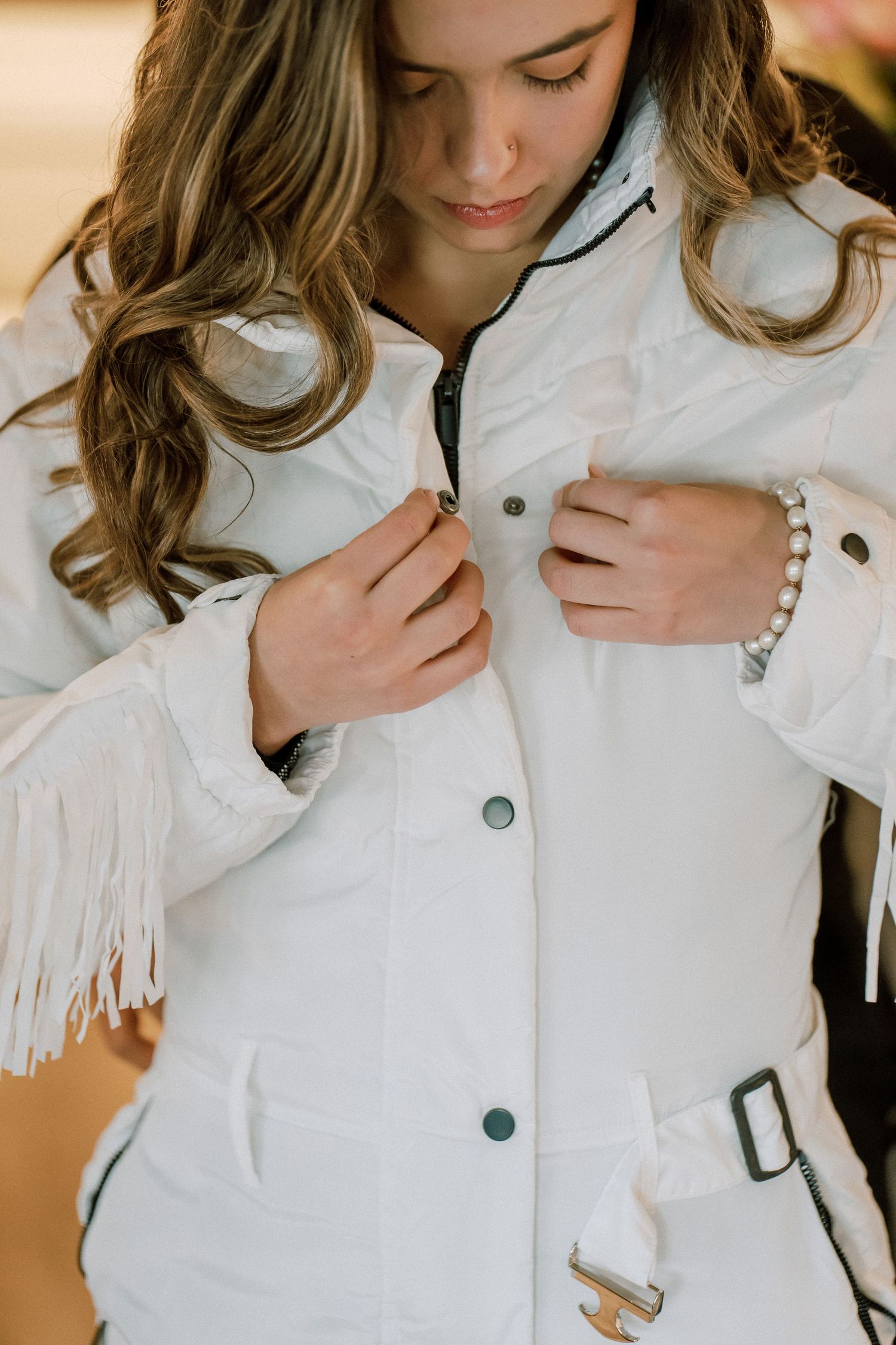 Four detail shots of someone wearing a white ruffle blouse with large buttons and white gloves.
