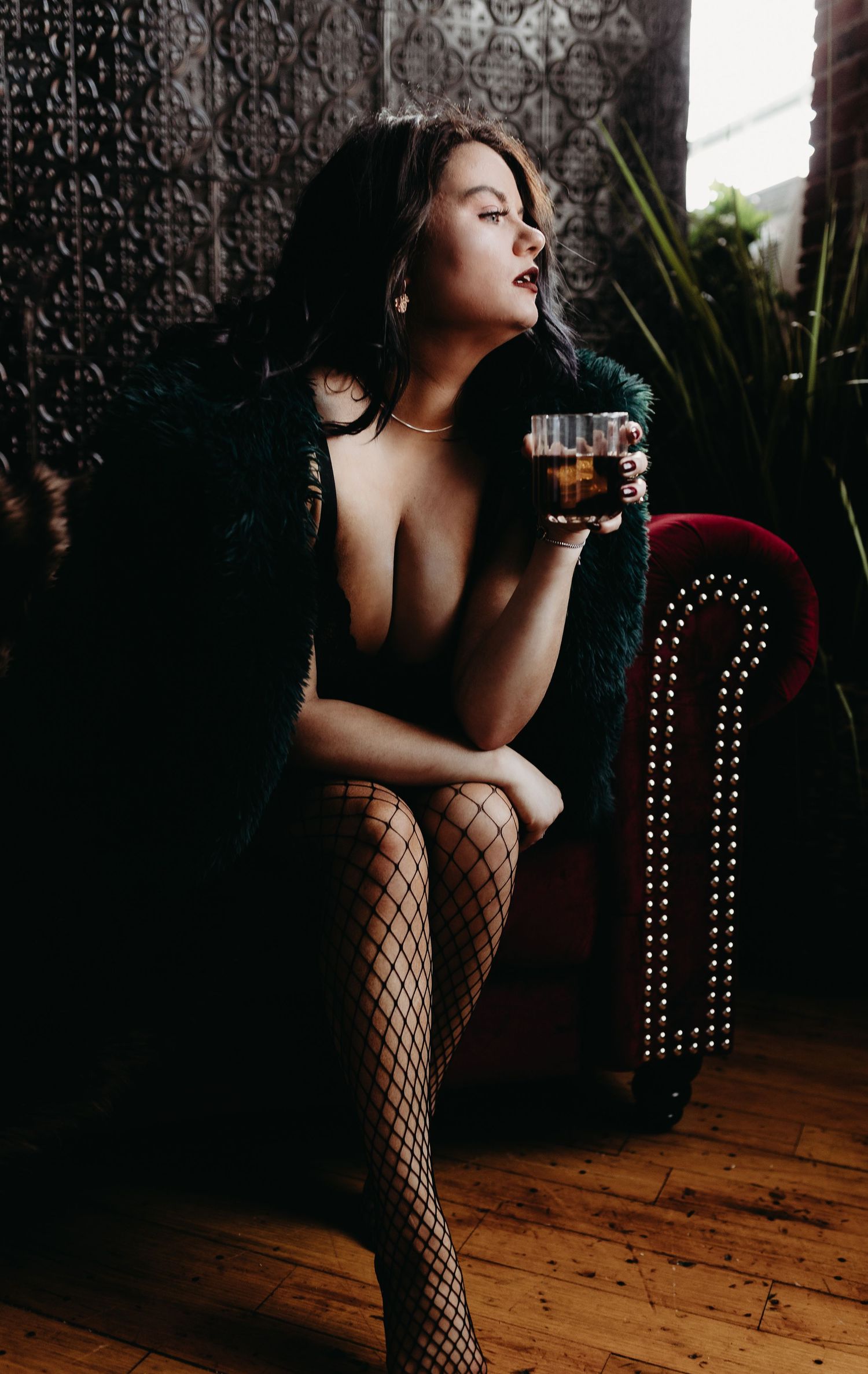 Moody boudoir portrait in fishnet stockings with dramatic lighting.
