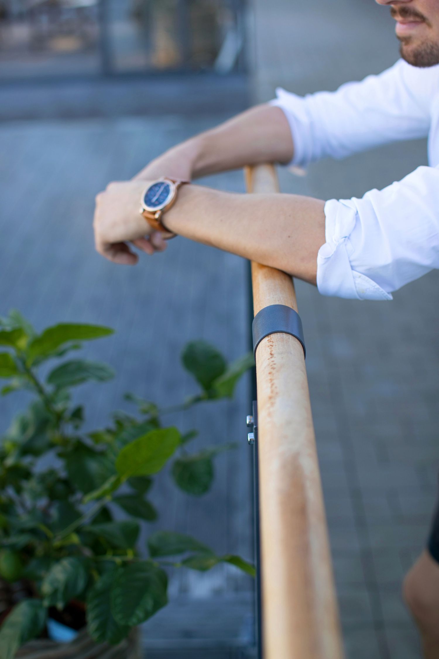Close-up of hands on wooden railing showing wristwatch detail.