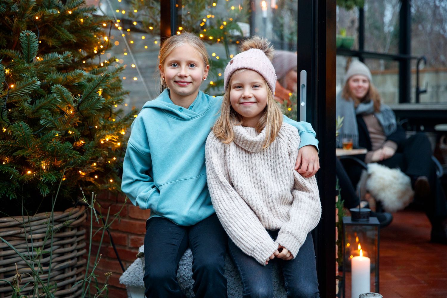 Cozy winter scene with decorated Christmas tree and glowing candlelight in the background.