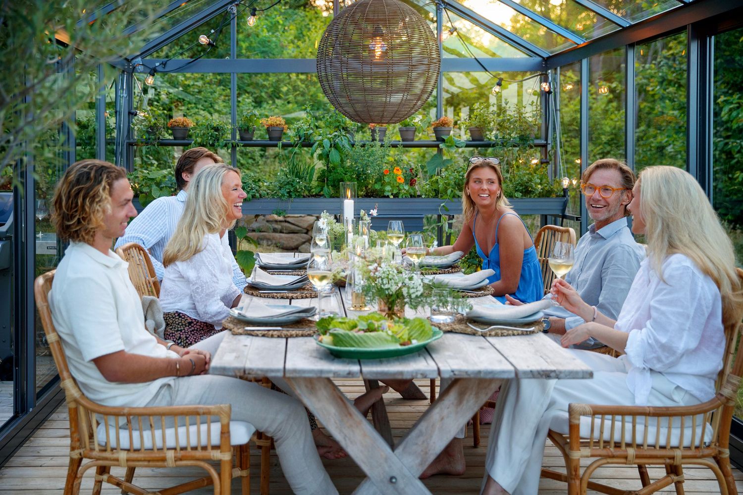 Guests dining in an elegant greenhouse in the evening.