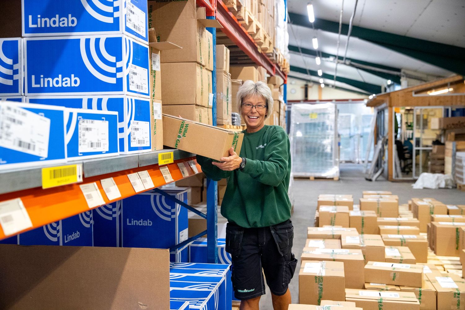 Warehouse worker organizing blue boxes on industrial storage shelves.