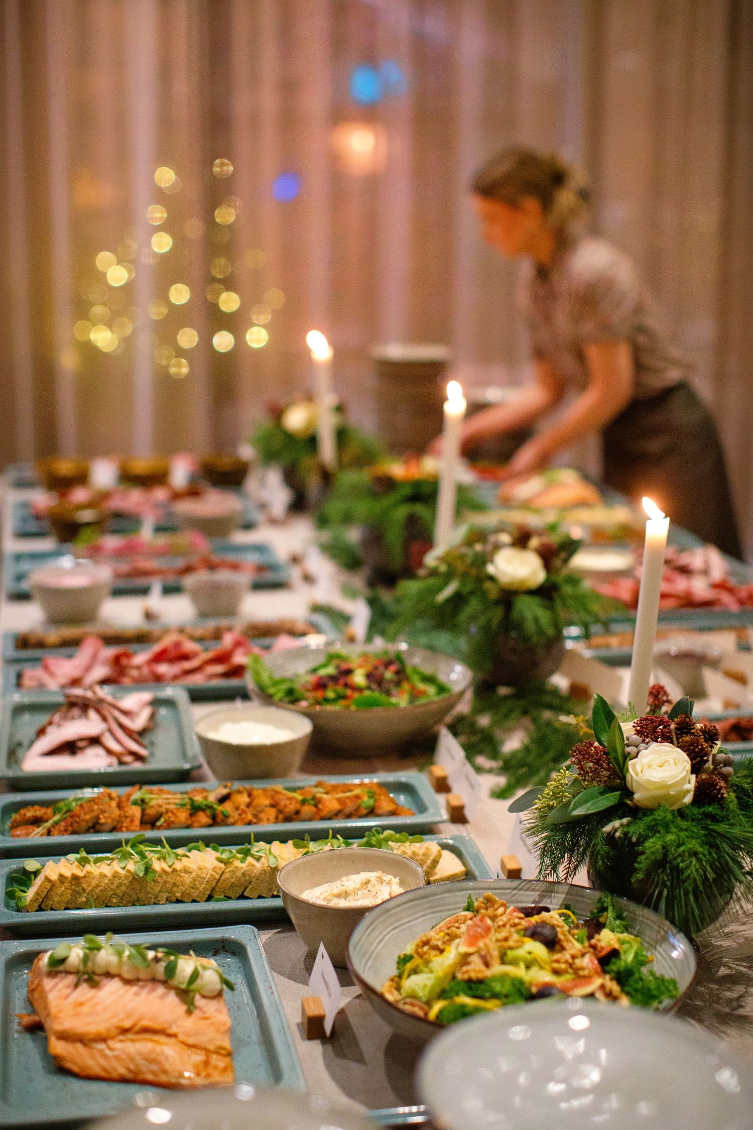 Elegant Christmas holiday dining table with salmon dishes, salads and festive centerpieces.