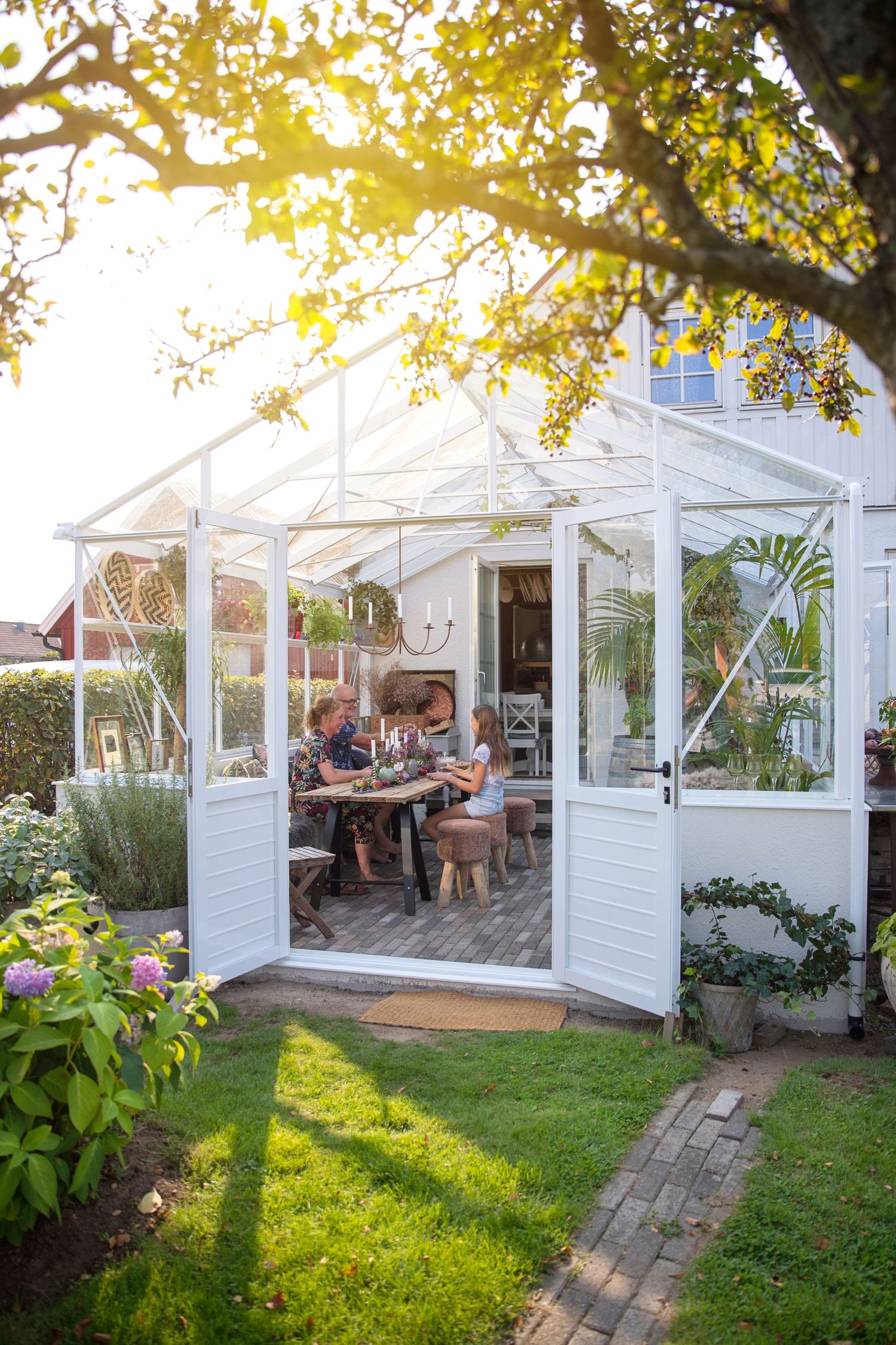Beautiful white greenhouse pavilion in garden setting during golden hour.