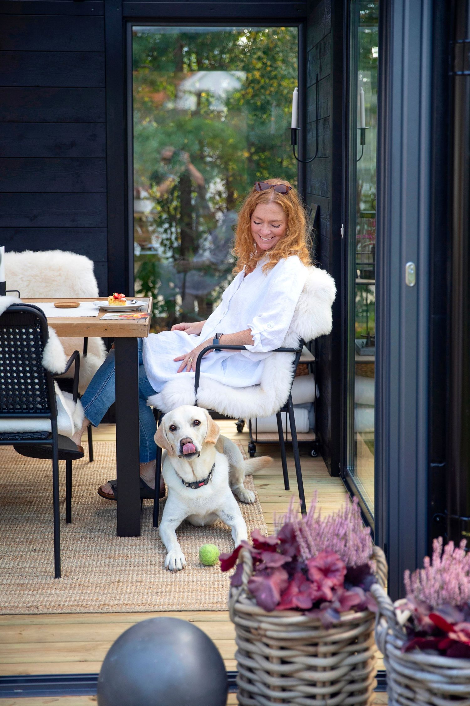 A relaxing patio scene with a happy white dog and decorative purple plants in baskets.