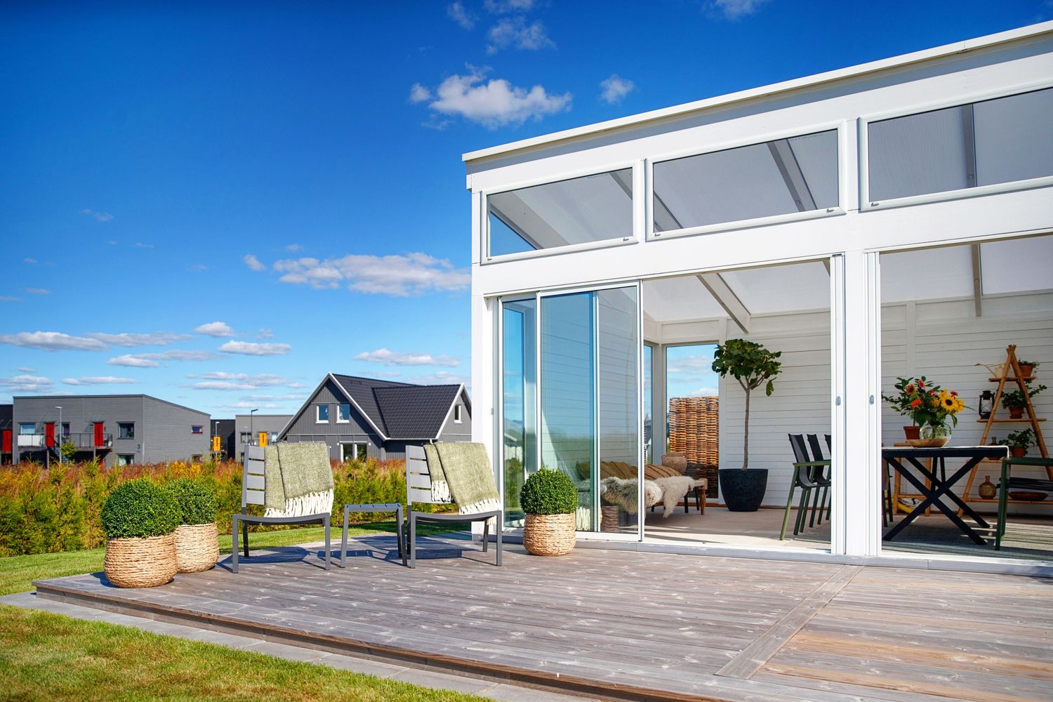 Modern house exterior with large windows and spacious wooden deck overlooking a scenic landscape.