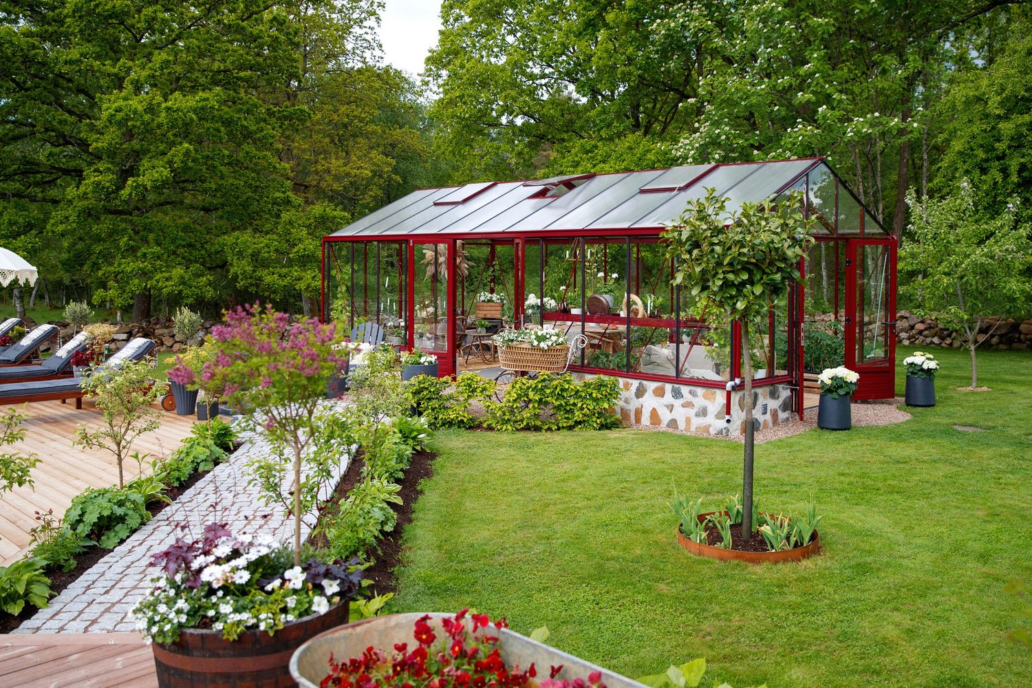 Scenic garden landscape with manicured lawns, blooming flowers, and a decorative red pavilion.
