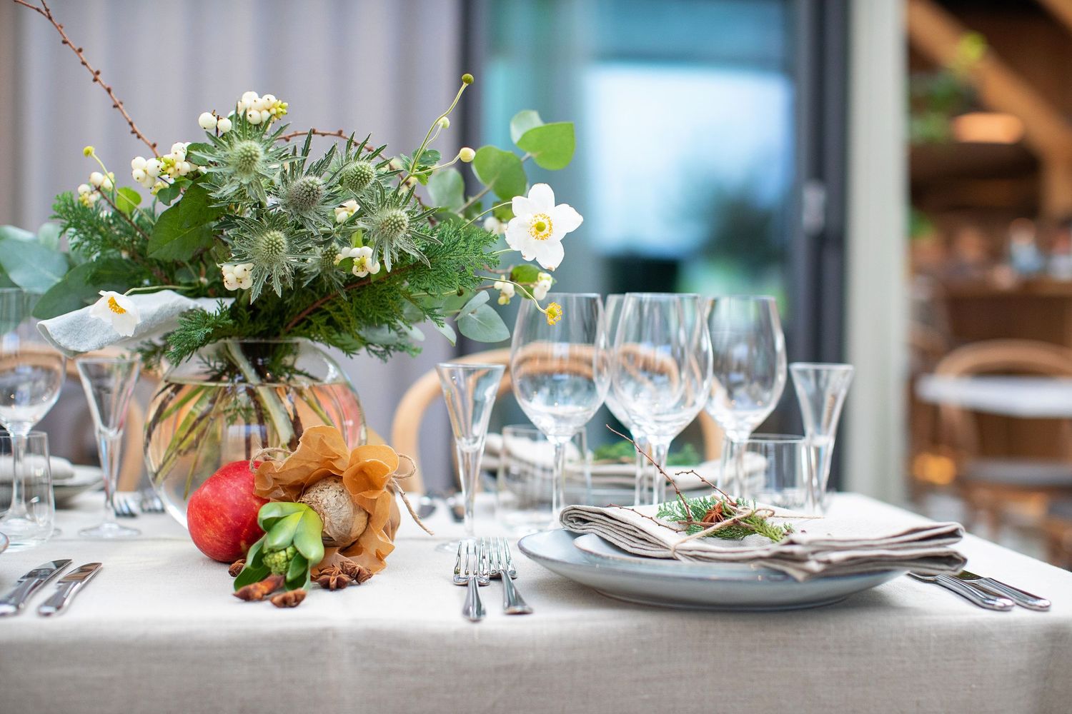 Formal dining table set with white linens, wine glasses, and fresh floral centerpiece.