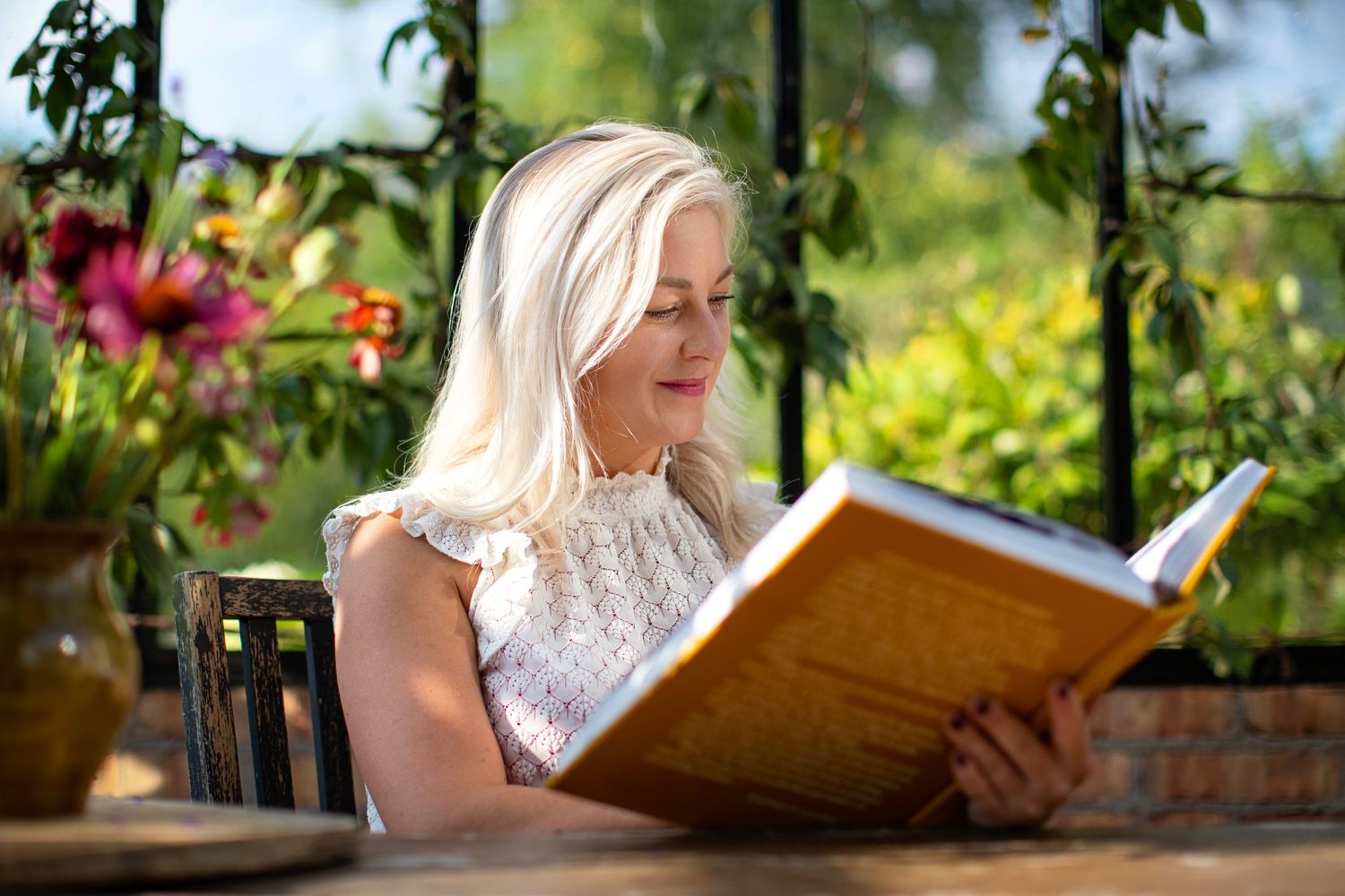 A peaceful outdoor reading moment in a garden with blooming flowers.