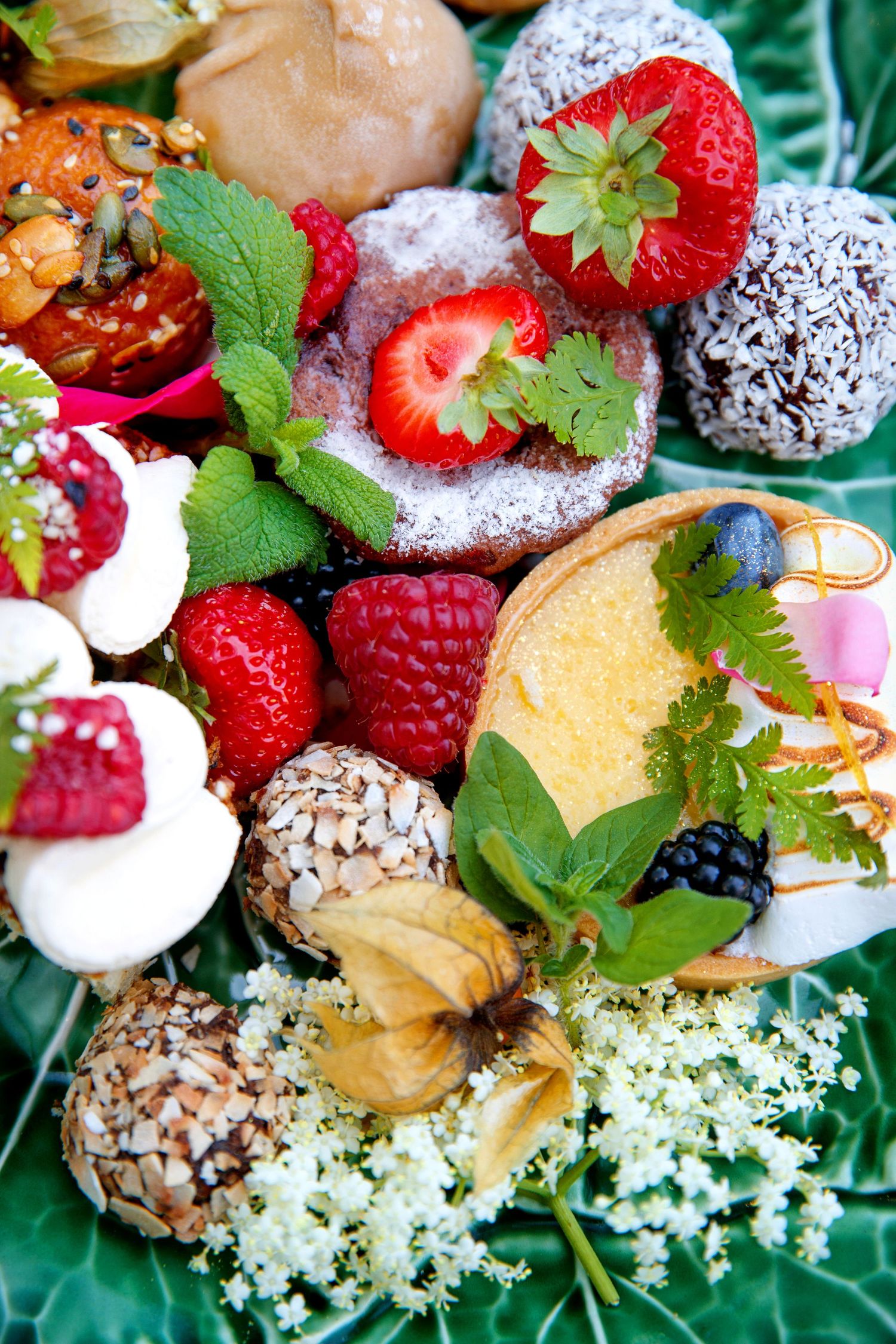 Colorful dessert platter with fresh berries, chocolates, and edible flowers.